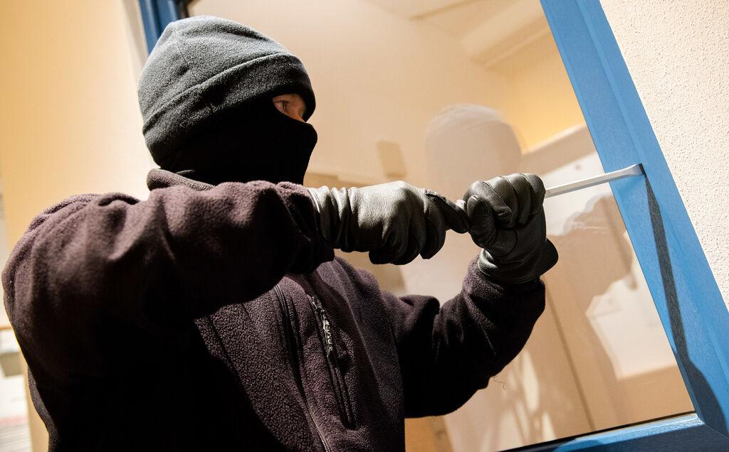 ARCHIV - 28.06.2016, Nordrhein-Westfalen, Hamburg: Ein als Einbrecher verkleideter Mann hebelt in der Kriminalpolizeilichen Beratungsstelle der Polizei ein Fenster auf. (zu dpa: «Mutmaßliche Mitglieder einer Einbrecherbande in U-Haft») Foto: Daniel Bockwoldt/dpa +++ dpa-Bildfunk +++