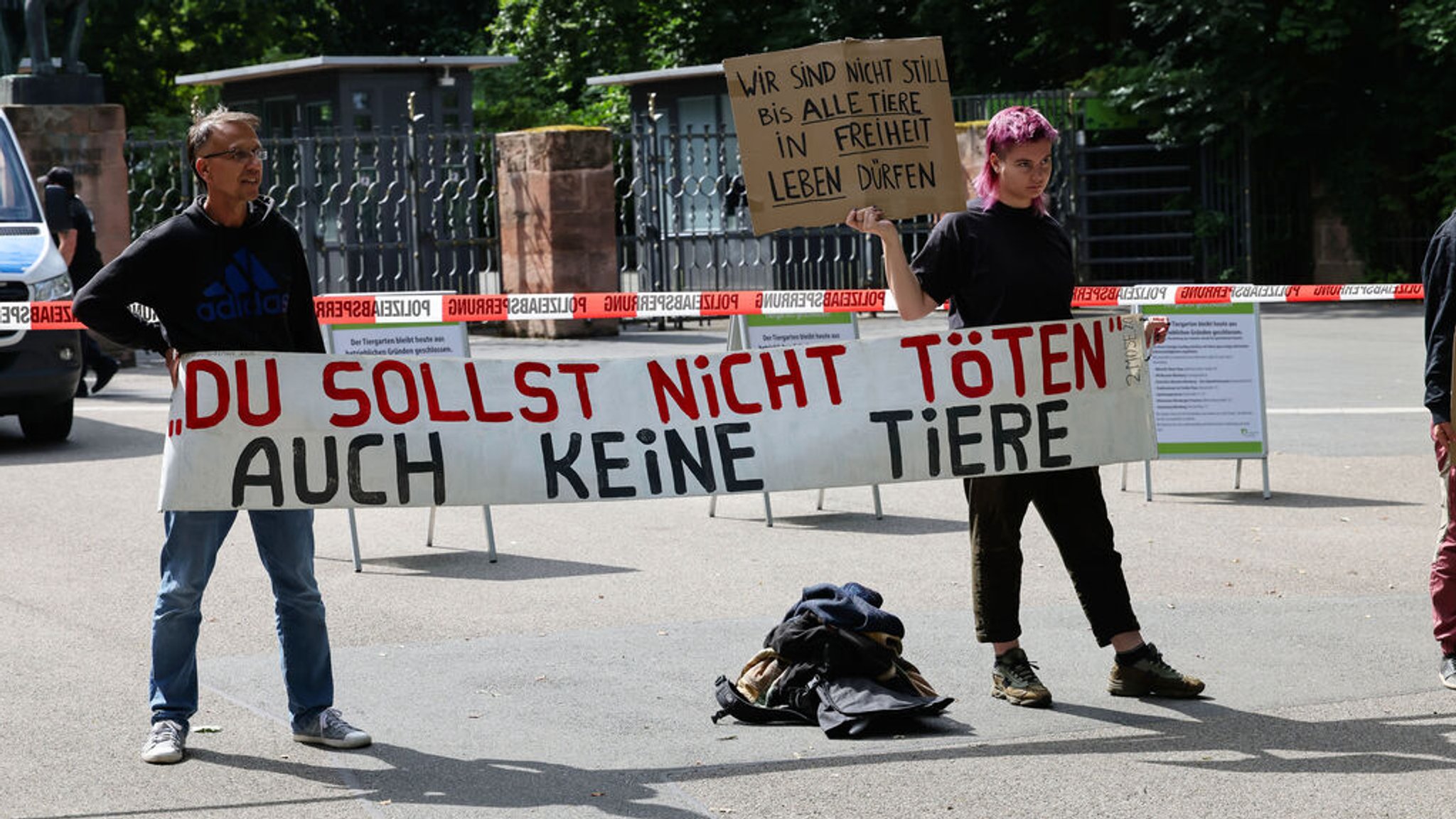 29.07.2025, Nürnberg: Animal Rebellion und vereinzelte Demonstranten anderer Gruppierungen stehen mit Protestschildern "Du Sollst nicht töten auch keine Tiere" und "Wir sind nicht still, bis alle Tiere in Freiheit leben" vor dem Tiergarten Nürnberg. 