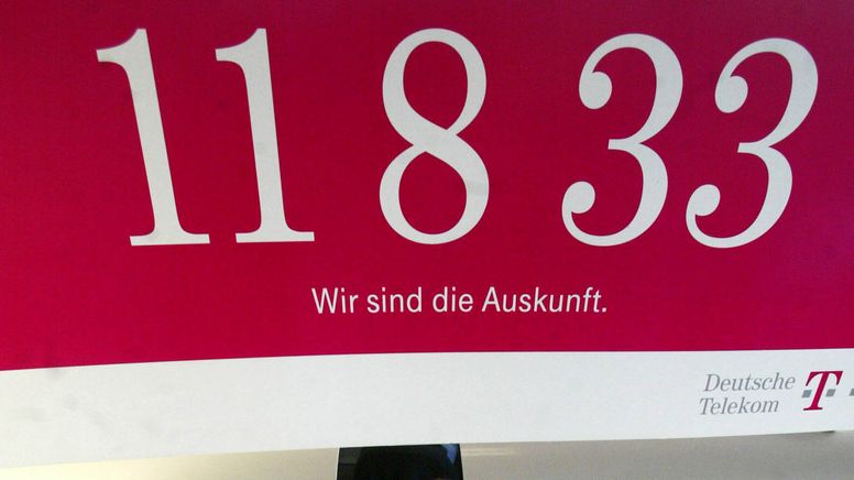 Ein Plakat der Telekom-Auskunft 11833 hängt über einem Büroarbeitsplatz. | Bild:picture-alliance/ ZB | Jens Wolf