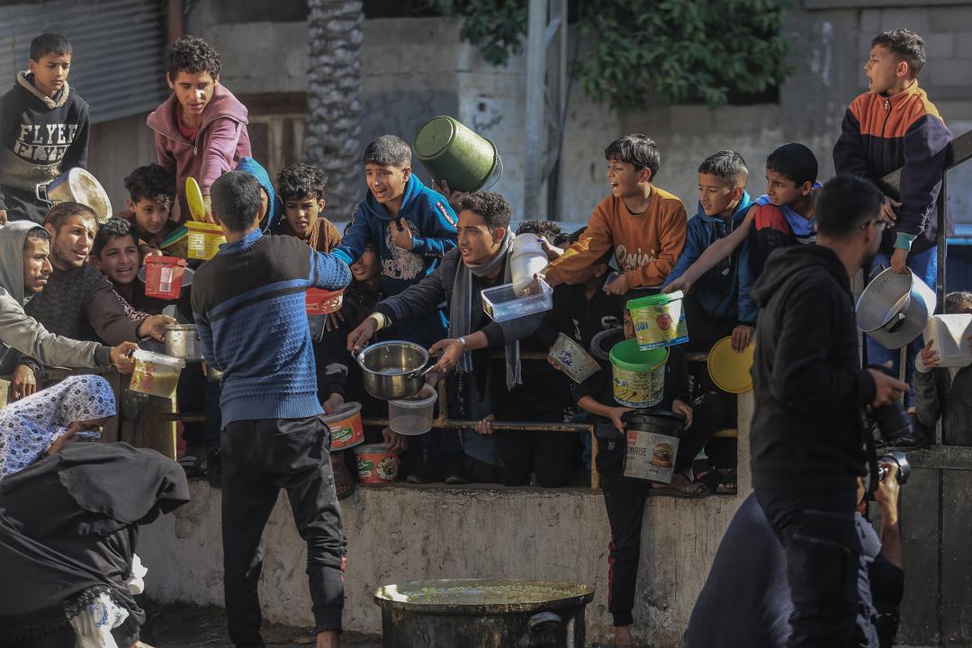 Palästinenser versammeln sich mit Töpfen, um an einer von einer Wohltätigkeitsorganisation eingerichteten Spendenstelle Lebensmittel entgegenzunehmen.