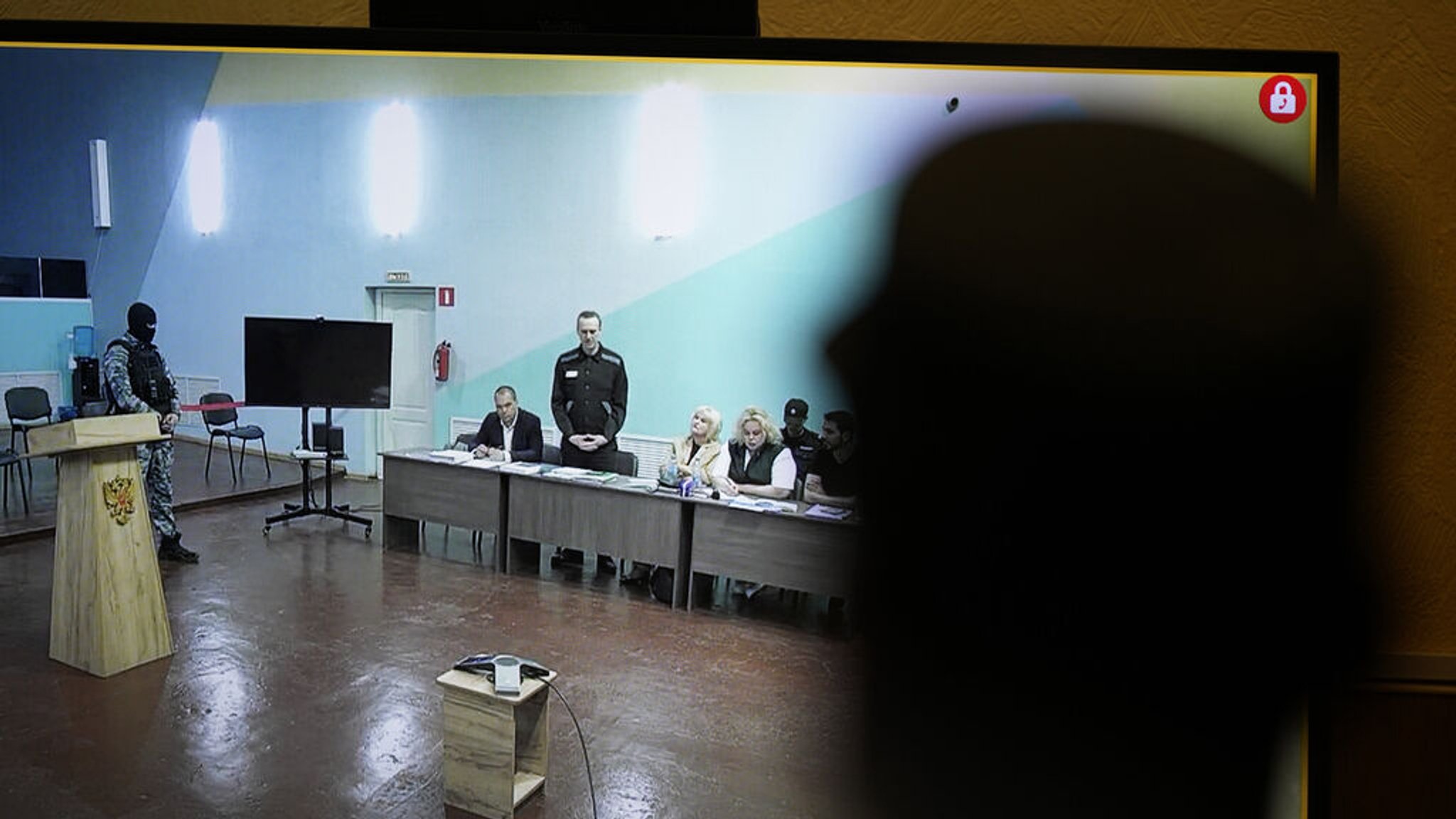 19.06.2023, Russland, Melechowo: Ein Beamter steht vor einem Monitor, der eine Live-Übertragung aus dem Verhandlungssaal zeigt, in dem Alexej Nawalny (3.v.l), Oppositionspolitiker aus Russland, während einer vorläufigen Anhörung in der Strafkolonie Melechowo spricht. In der Strafkolonie Melechowo findet der Prozess gegen den prominentesten Gegner von Kremlchef Putin statt. Dem bereits inhaftierten Politiker wird Extremismus vorgeworfen. Bei einer Verurteilung droht ihm eine weitere lange Haftstrafe. Foto: Alexander Zemlianichenko/AP/dpa +++ dpa-Bildfunk +++