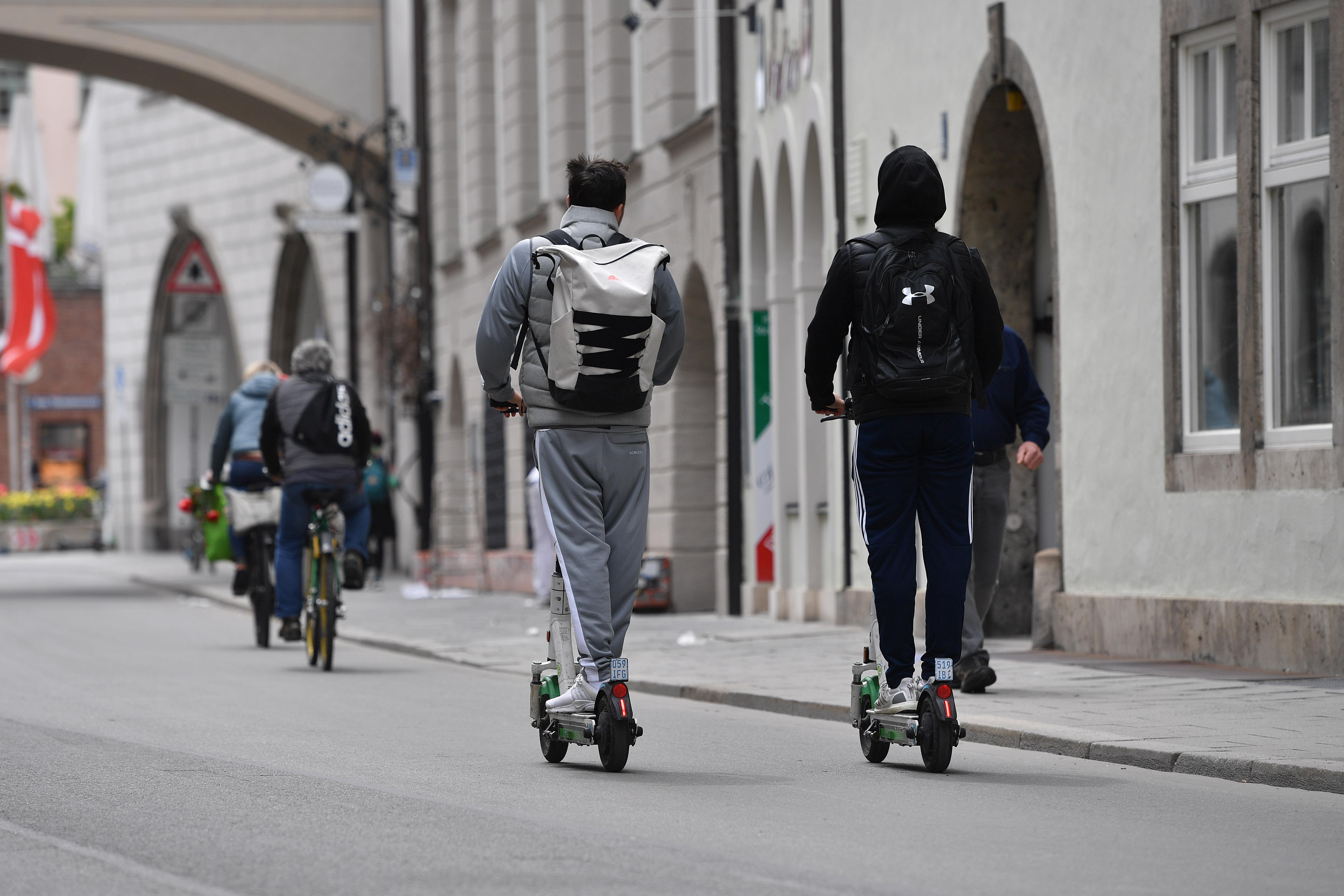 E-Scooter, Radfahrer und Fußgänger auf der Straße im Stadtzentrum in München.
