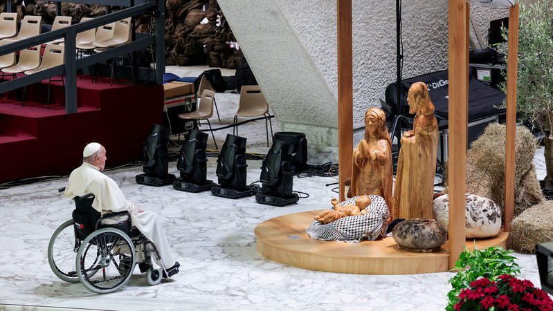 Papst Franziskus im Rollstuhl vor einer Krippe. Darin liegt das Jesuskind, gebettet auf einem schwarz-weißen Palästinensertuch, der sogenannten Kufiya | Bild: Reuters Papst Franziskus im Rollstuhl vor einer Krippe. Darin liegt das Jesuskind, gebettet auf einem schwarz-weißen Palästinensertuch, der sogenannten Kufiya
