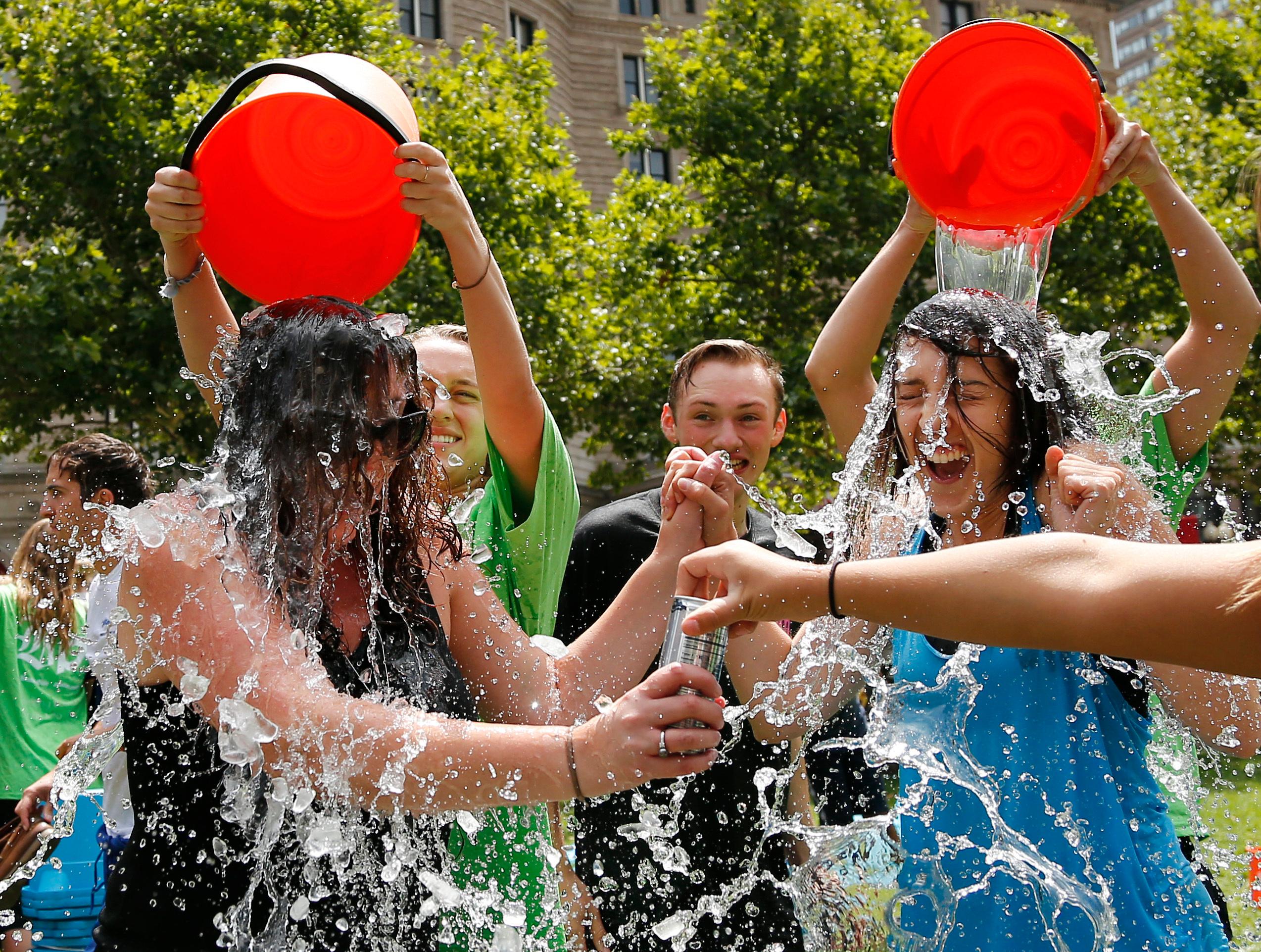 Junge Menschen werden für die Ice Bucket Challenge mit eimerweise Eiswasser übergossen.
