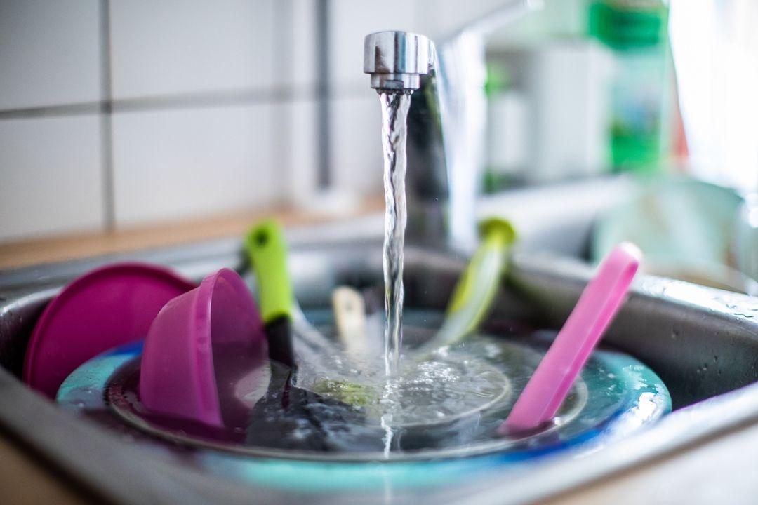 Wasser läuft aus einem Wasserhahn in ein Spülbecken.