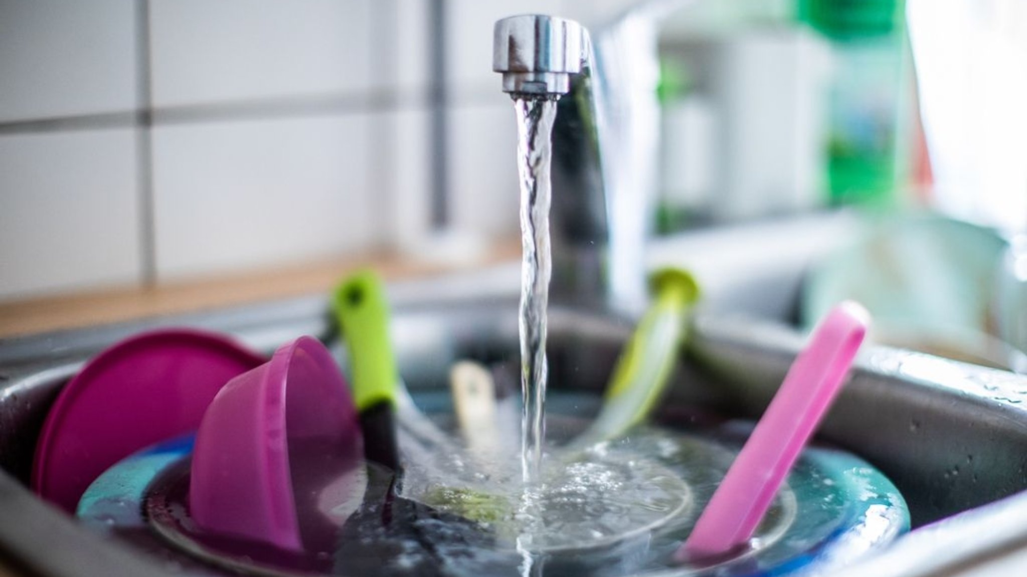 Wasser läuft aus einem Wasserhahn in ein Spülbecken.