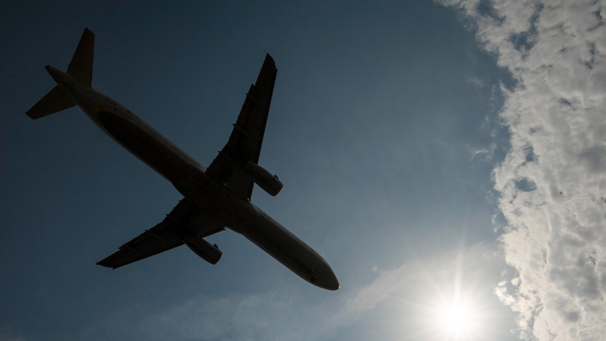 Vorbei an einem Wolkenfeld landet eine Passagiermaschine auf dem Flughafen. 