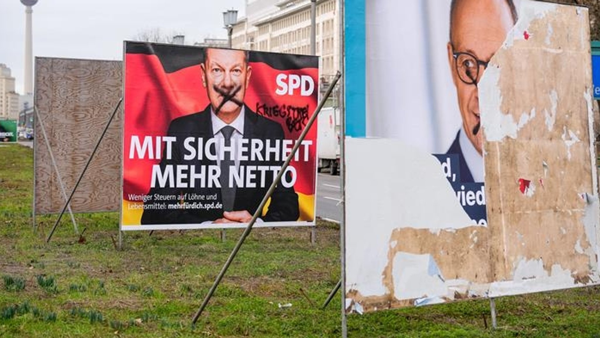 Beschädigte Plakate der Parteien SPD und CDU mit Portraits von Bundeskanzler Olaf Scholz und Friedrich Merz.