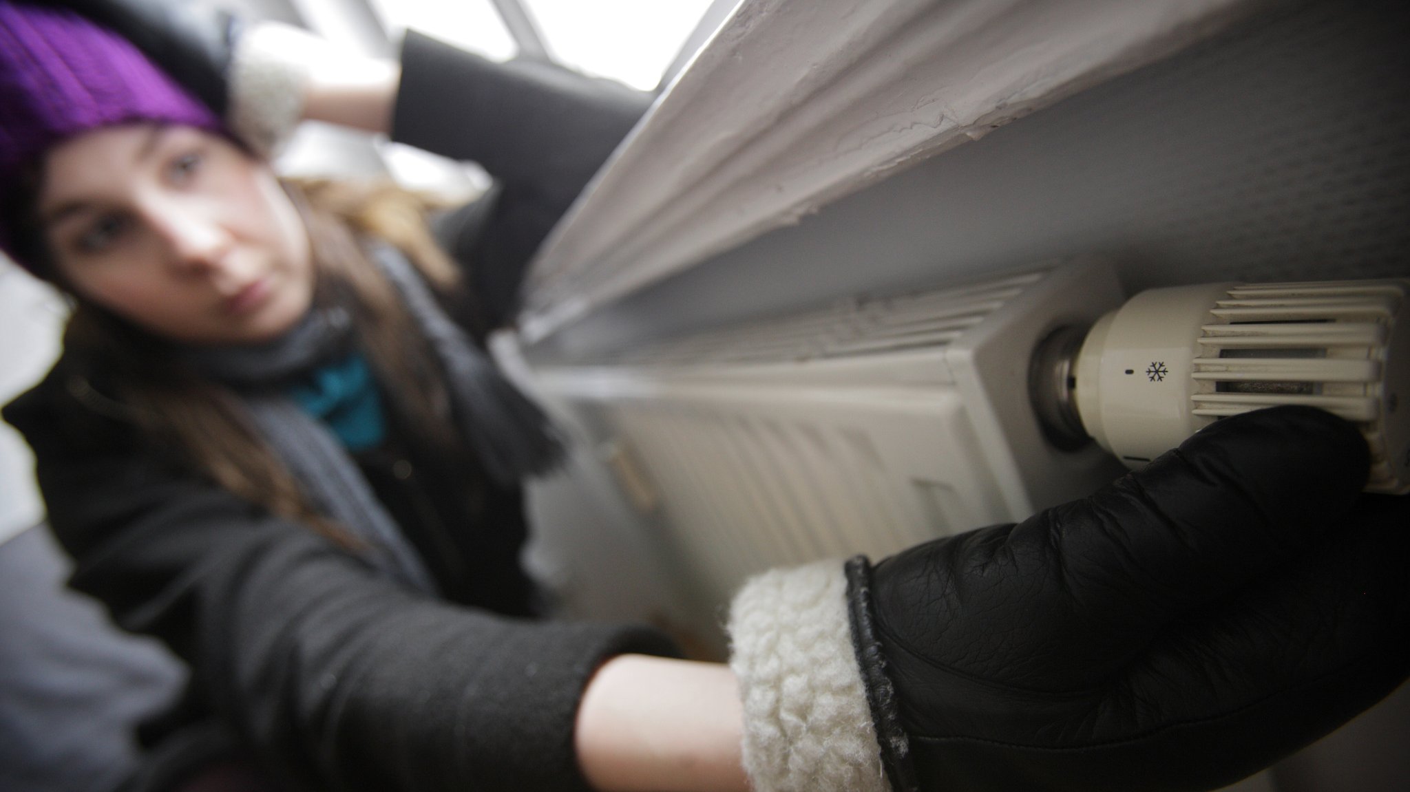 (Symbolbild) Eine Frau mit Mütze, Schal und Handschuhen bekleidet sitzt an einer ausgefallenen Heizung | Bild: picture alliance / photothek | Thomas Trutschel (Symbolbild) Eine Frau mit Mütze, Schal und Handschuhen bekleidet sitzt an einer ausgefallenen Heizung