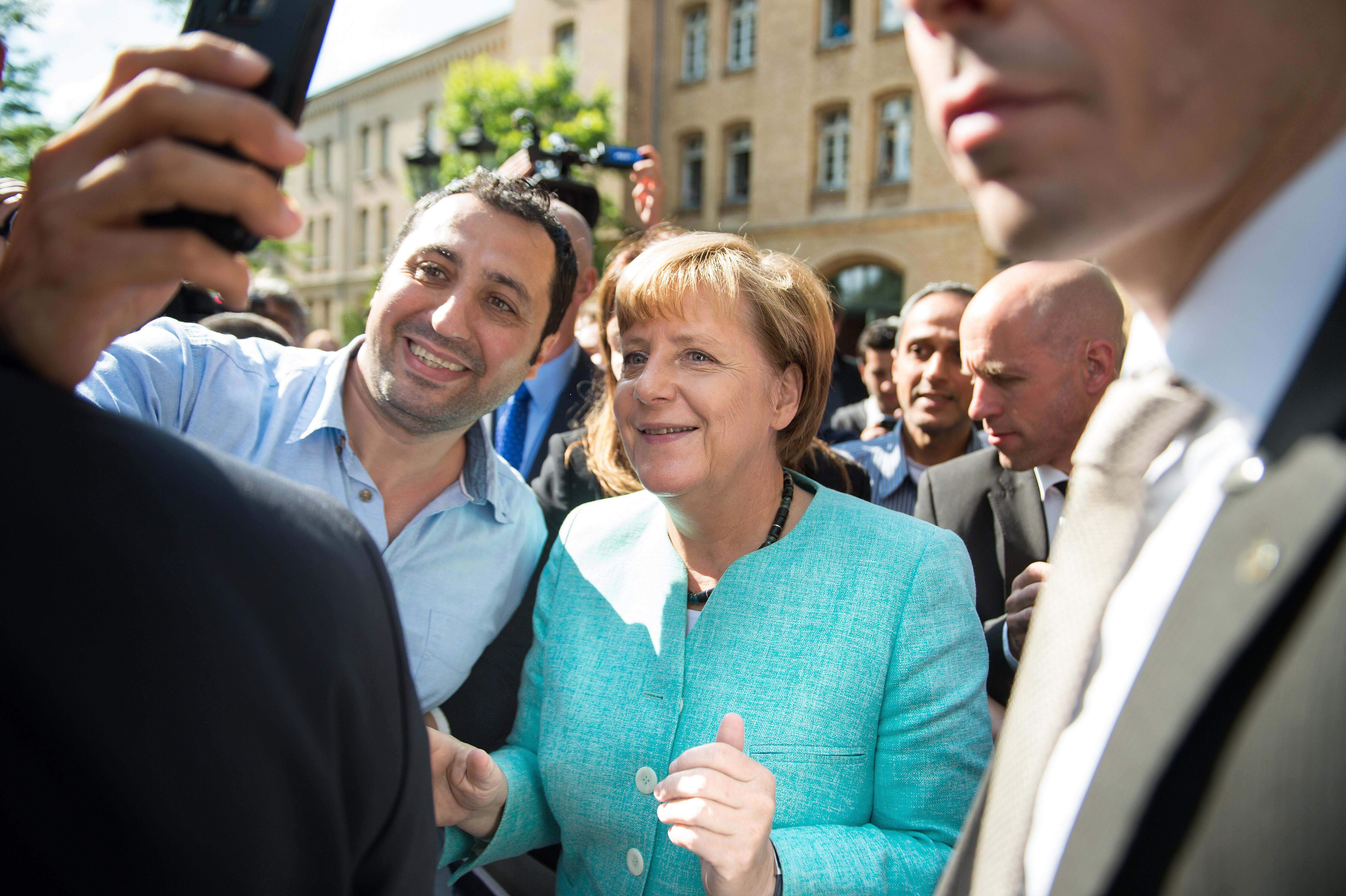 Merkel am 10.09.2015 nach dem Besuch einer Erstaufnahmeeinrichtung für Asylbewerber in Berlin-Spandau bei einem Selfie mit einem Geflüchteten.