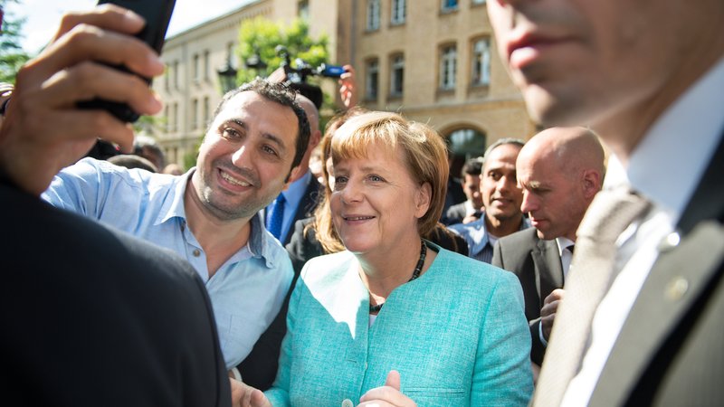 Merkel am 10.09.2015 nach dem Besuch einer Erstaufnahmeeinrichtung für Asylbewerber in Berlin-Spandau bei einem Selfie mit einem Geflüchteten. | Bild: picture alliance / dpa | Bernd Von Jutrczenka Merkel am 10.09.2015 nach dem Besuch einer Erstaufnahmeeinrichtung für Asylbewerber in Berlin-Spandau bei einem Selfie mit einem Geflüchteten.