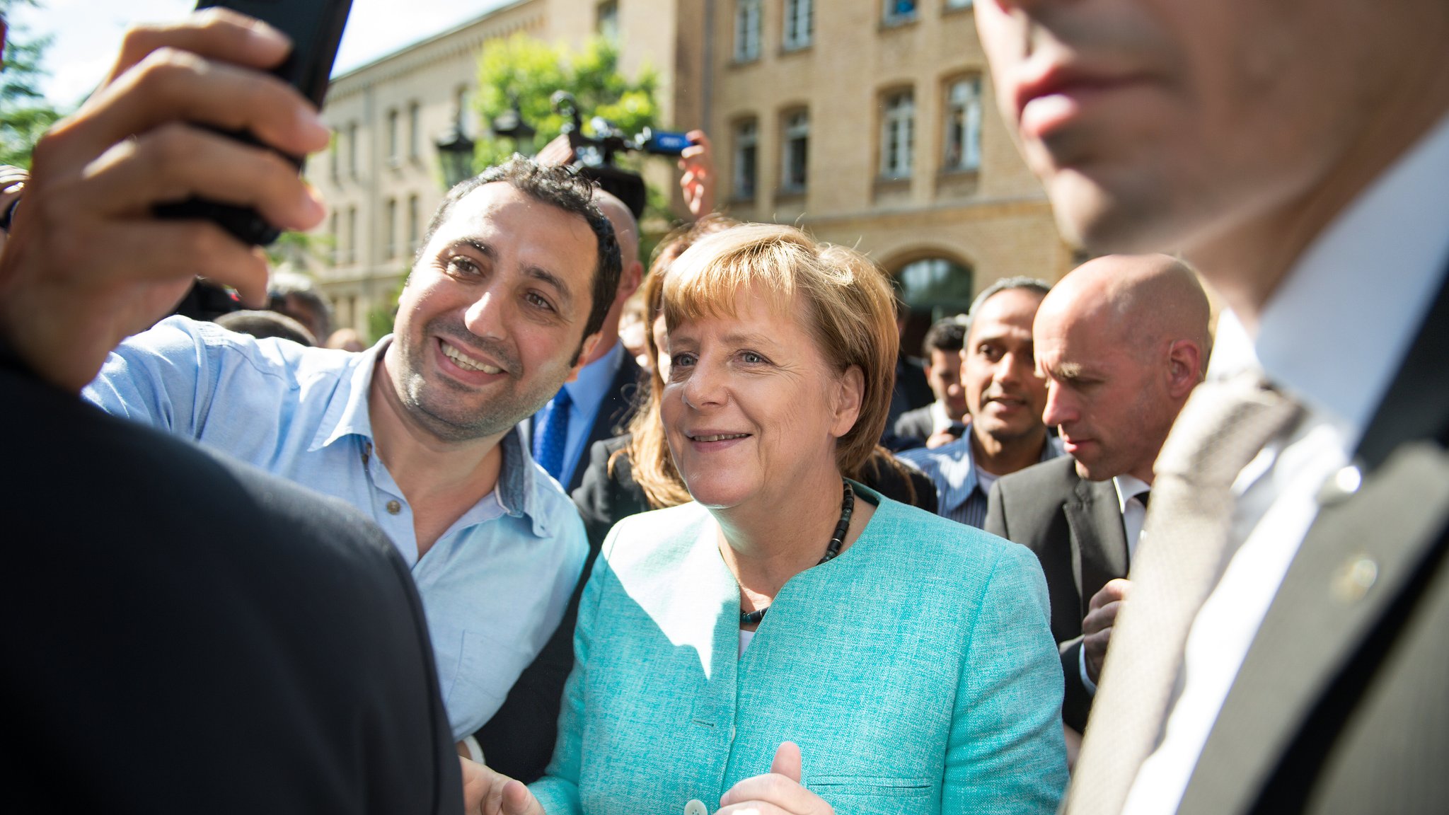 Merkel am 10.09.2015 nach dem Besuch einer Erstaufnahmeeinrichtung für Asylbewerber in Berlin-Spandau bei einem Selfie mit einem Geflüchteten.