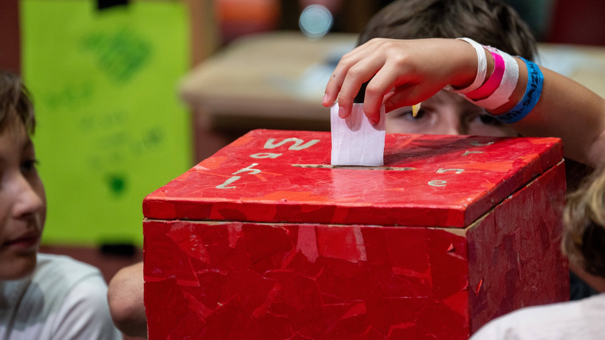 Kinder stecken Wahlzettel in eine selbst gebastelte Wahlurne 