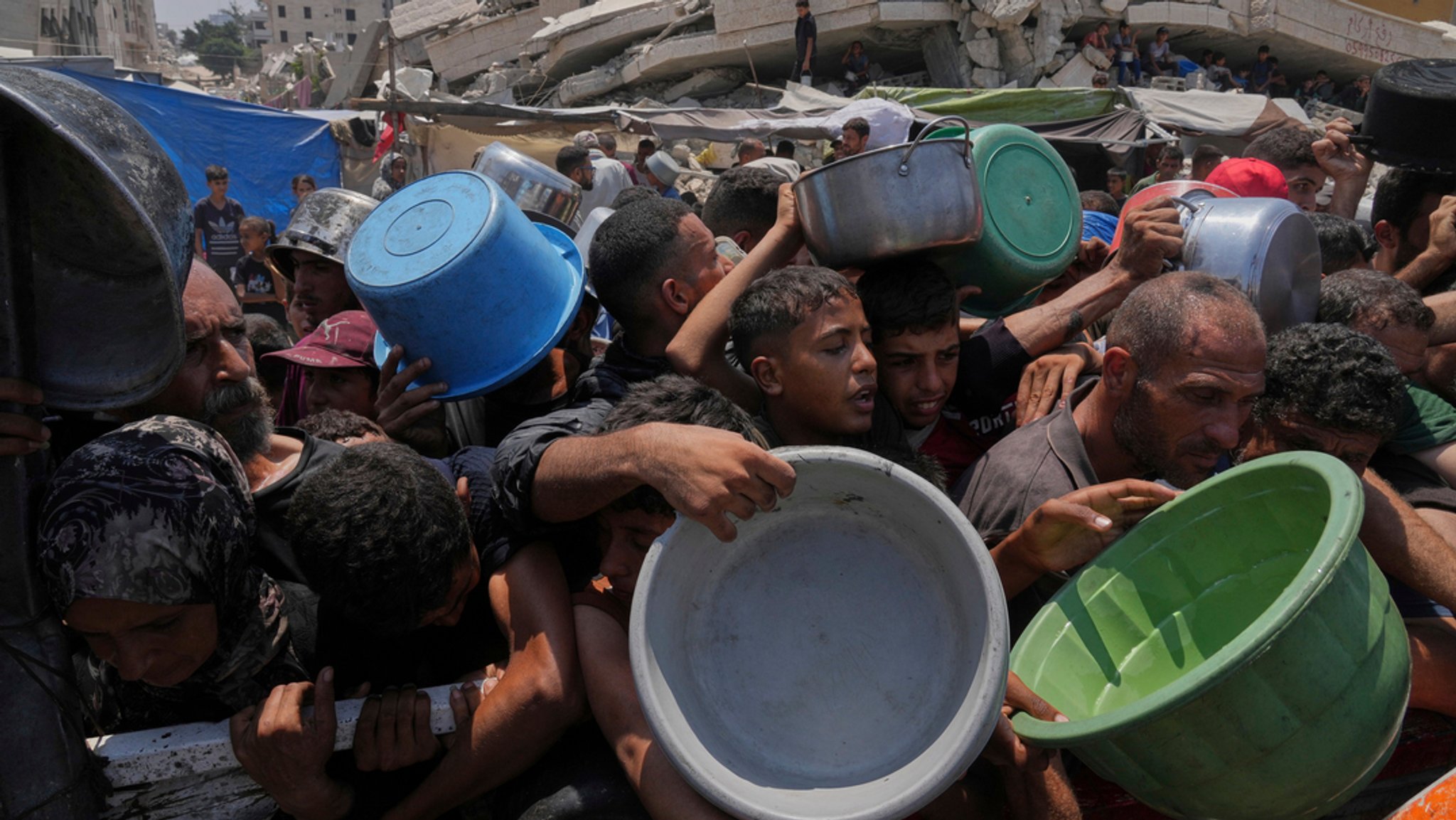 26.07.2025, Palästinensische Gebiete, Gaza-Stadt: Palästinenser kämpfen um gespendete Lebensmittel in einer Gemeinschaftsküche in Gaza-Stadt im nördlichen Gazastreifen.