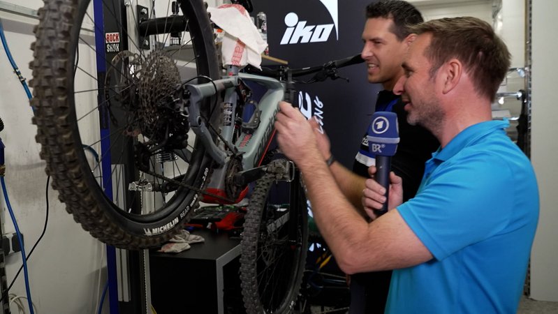 Martin Breitkopf prüft  mit einem Mechaniker ein Fahrrad