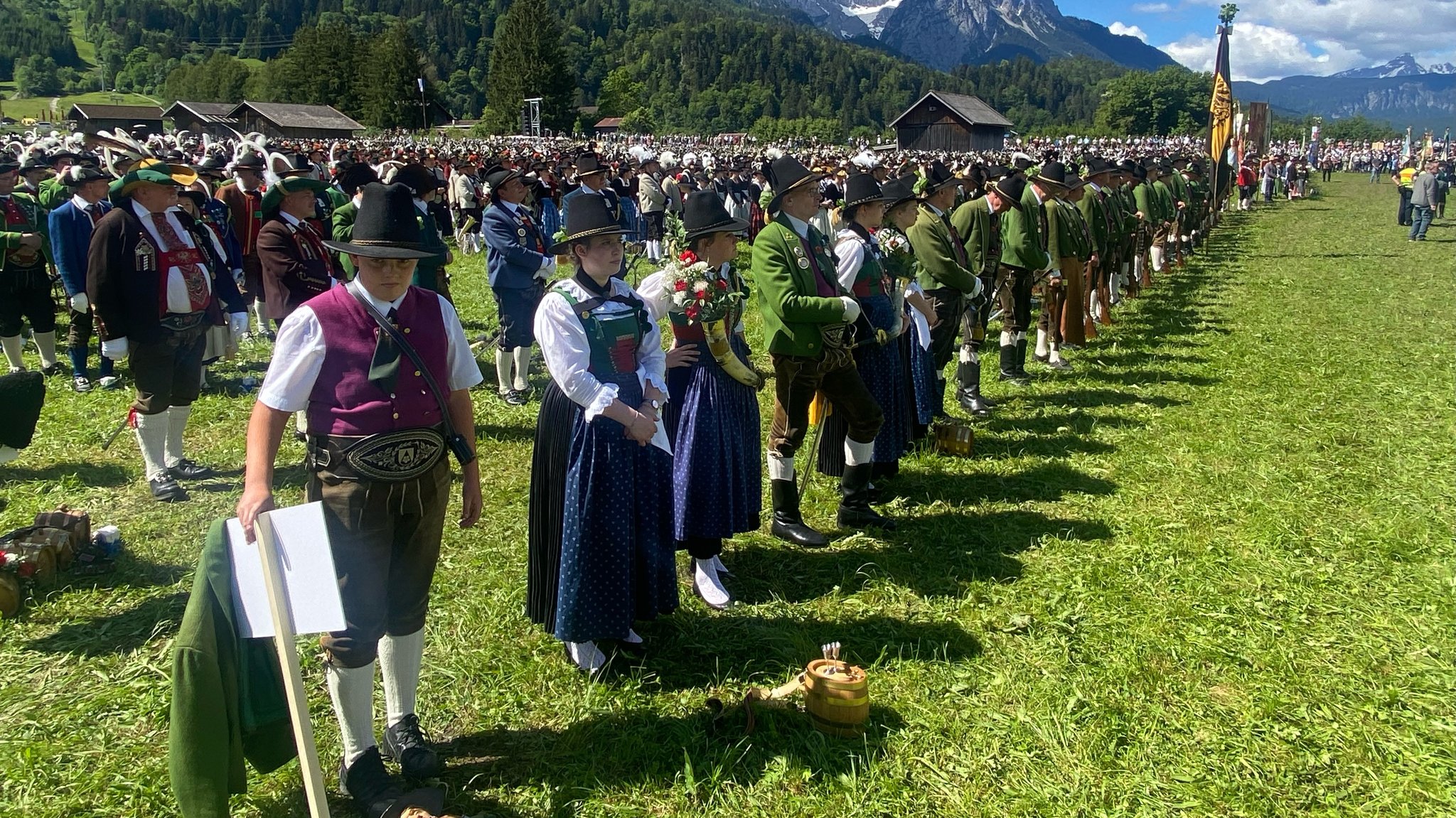 Mehrere Hundert Gebirgsschützen stehen in Tracht auf einer Wiese