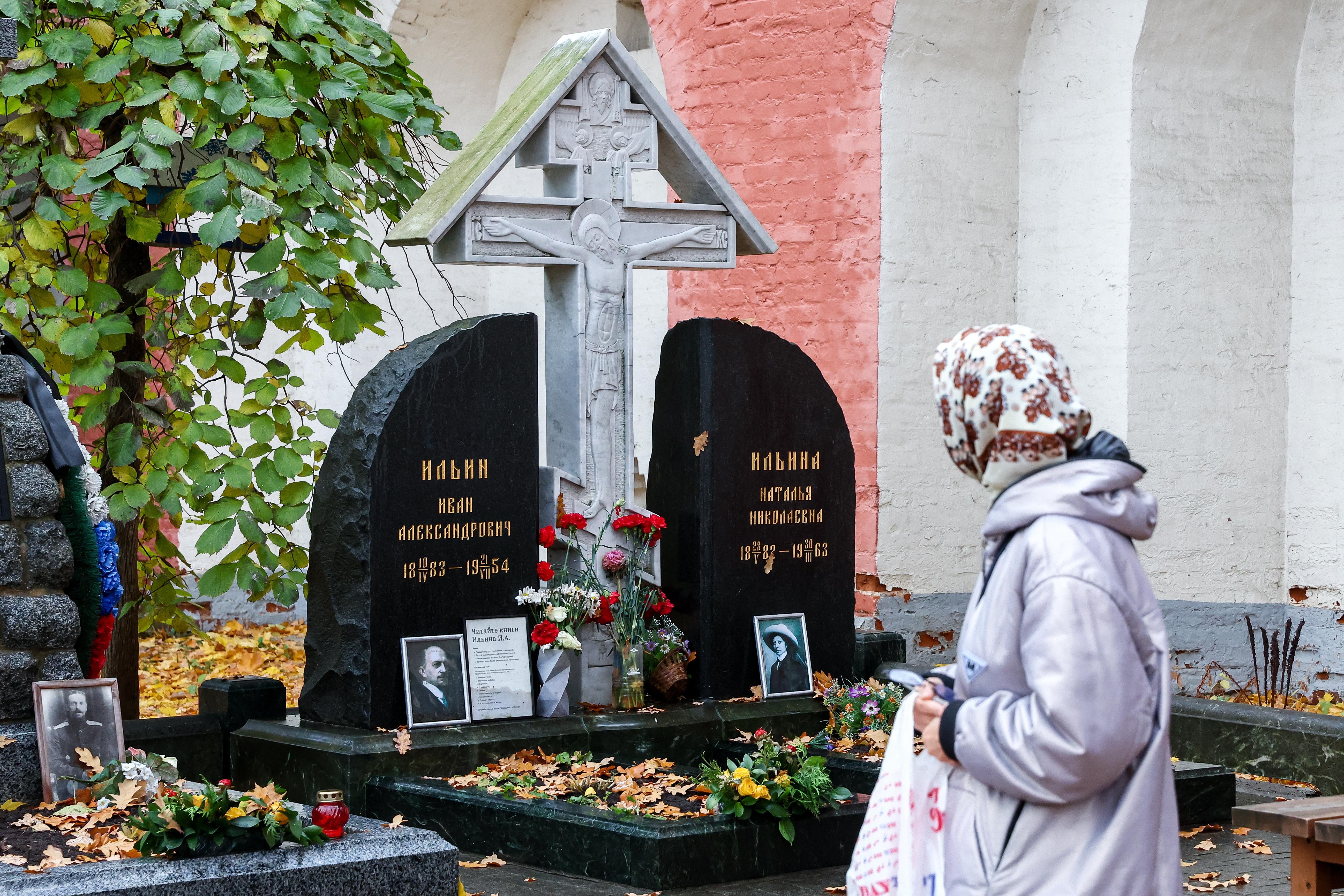 Friedhofsbesucherin mit Kopftuch schaut auf Grabstein