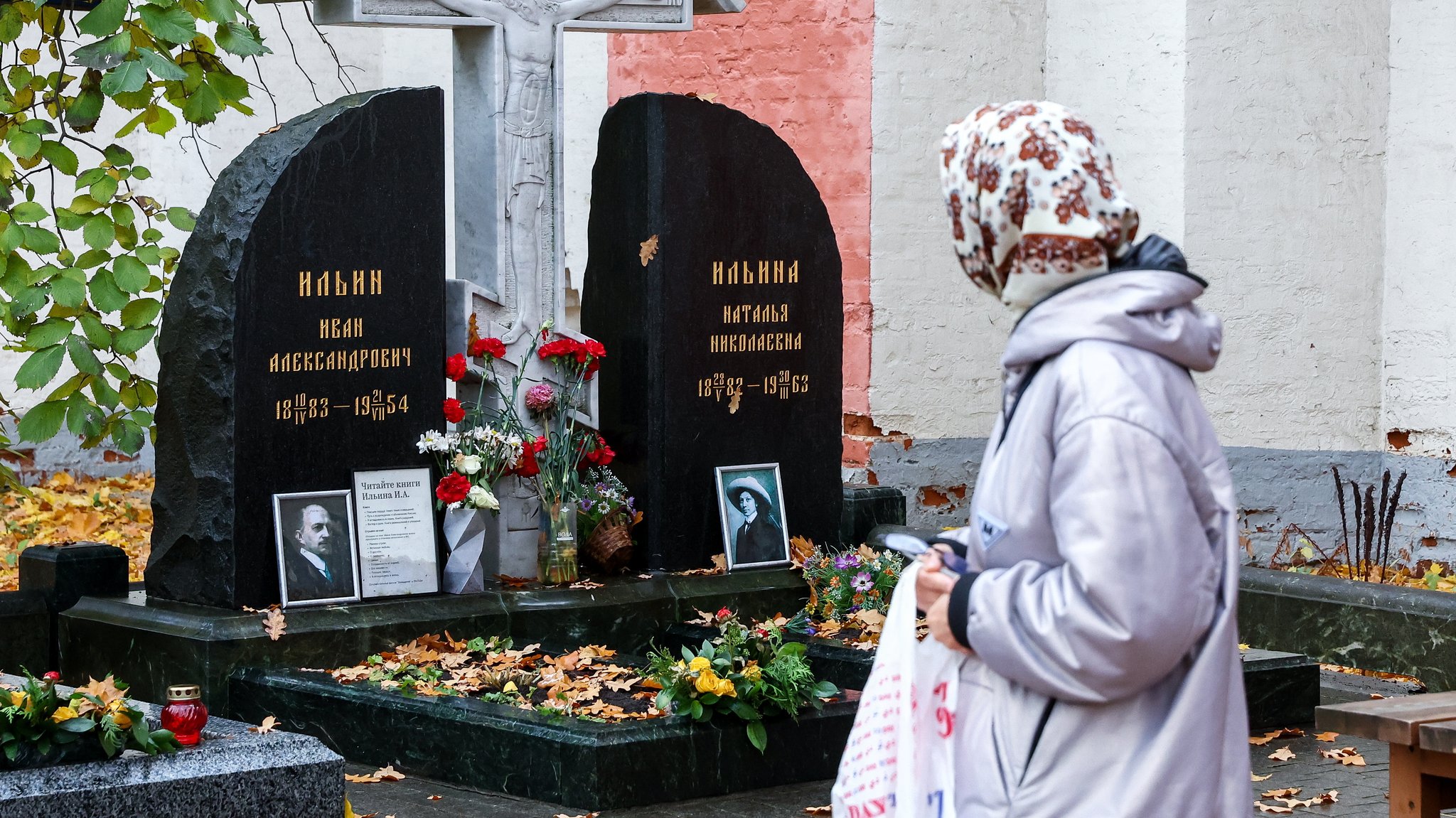 Friedhofsbesucherin mit Kopftuch schaut auf Grabstein