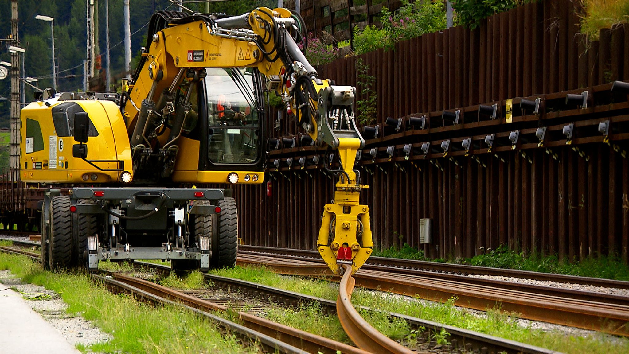 Ein Bagger biegt eine Bahnschiene um.