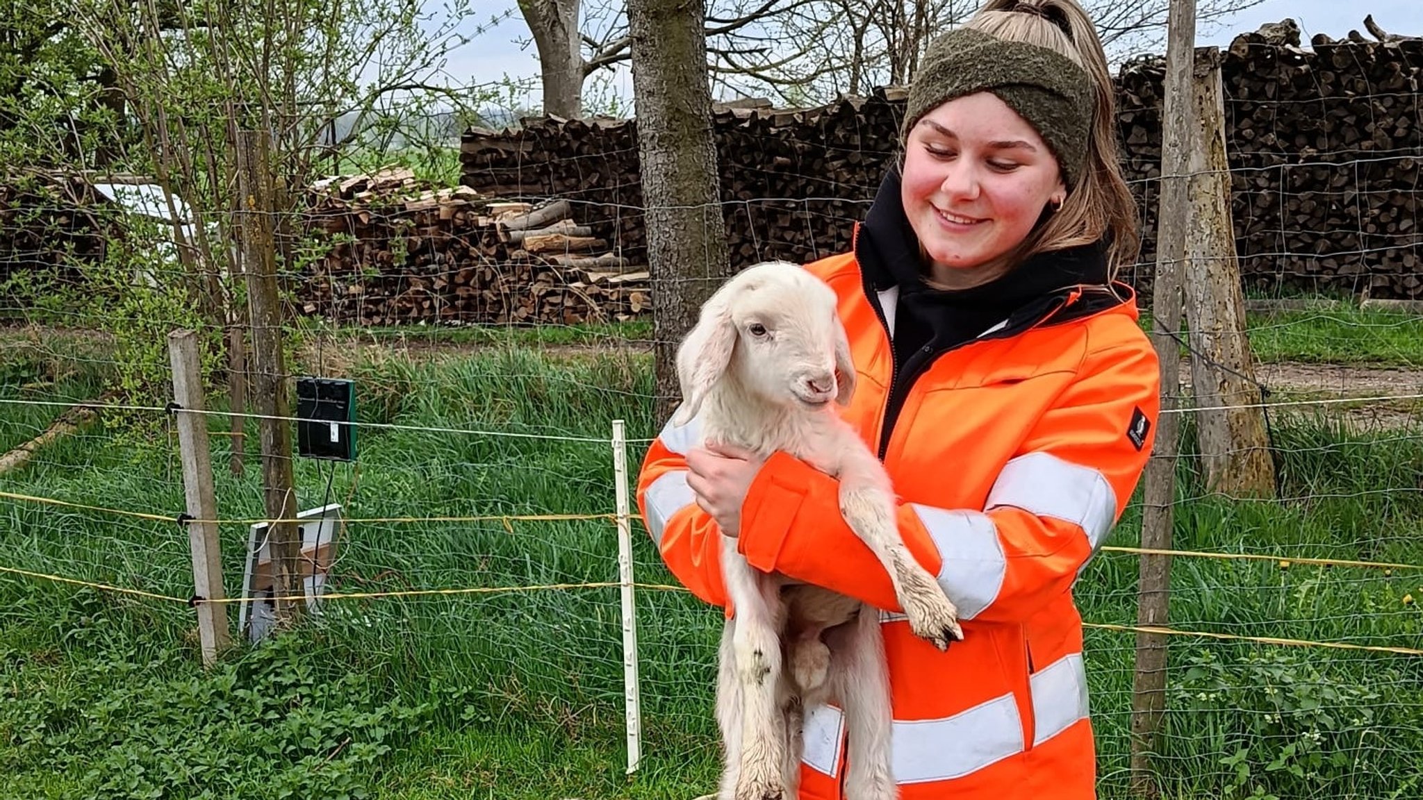 Eine junge Frau in einer Jacke in orangener Signalfarbe hält ein Lamm auf dem Arm | Bild: Stadt Günzburg Eine junge Frau in einer Jacke in orangener Signalfarbe hält ein Lamm auf dem Arm