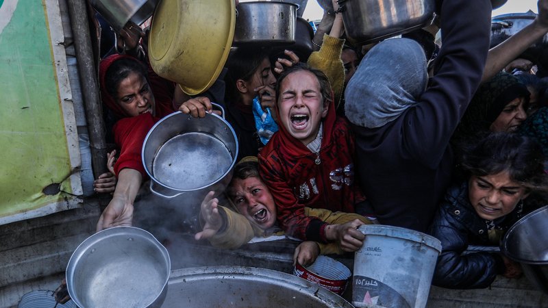 Gazastreifen: Frauen und Kinder mit leeren Töpfen versuchen, eine Essensration abzubekommen. | Bild: picture alliance / Anadolu | Abed Rahim Khatib Gazastreifen: Frauen und Kinder mit leeren Töpfen versuchen, eine Essensration abzubekommen.