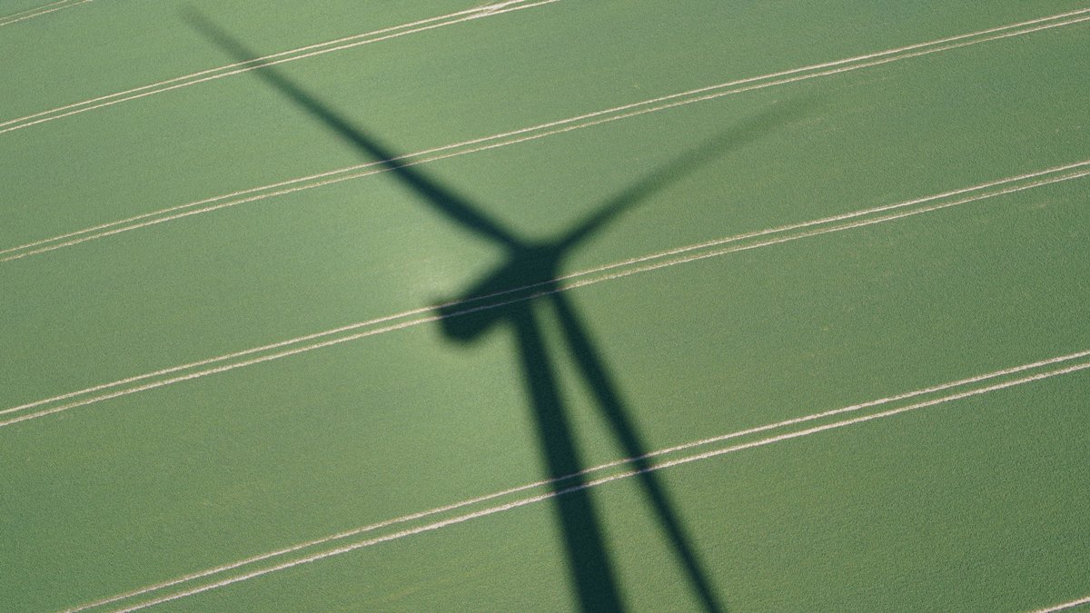 Schatten einer Windenergieanlage auf einem grünen Feld  (Symbolbild).