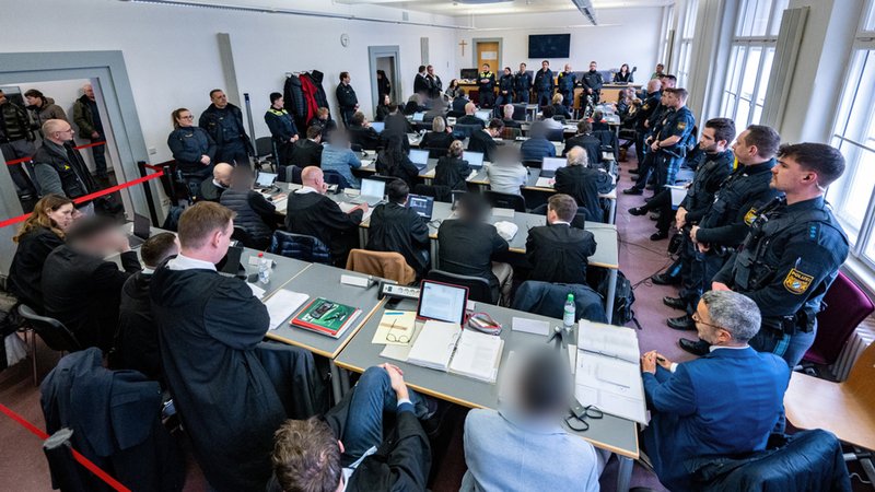 Die Angeklagten sitzen zwischen ihren Anwälten und Übersetzern umringt von Polizisten im Verhandlungssaal des Landgerichts. | Bild: Armin Weigel/dpa-Bildfunk Die Angeklagten sitzen zwischen ihren Anwälten und Übersetzern umringt von Polizisten im Verhandlungssaal des Landgerichts.