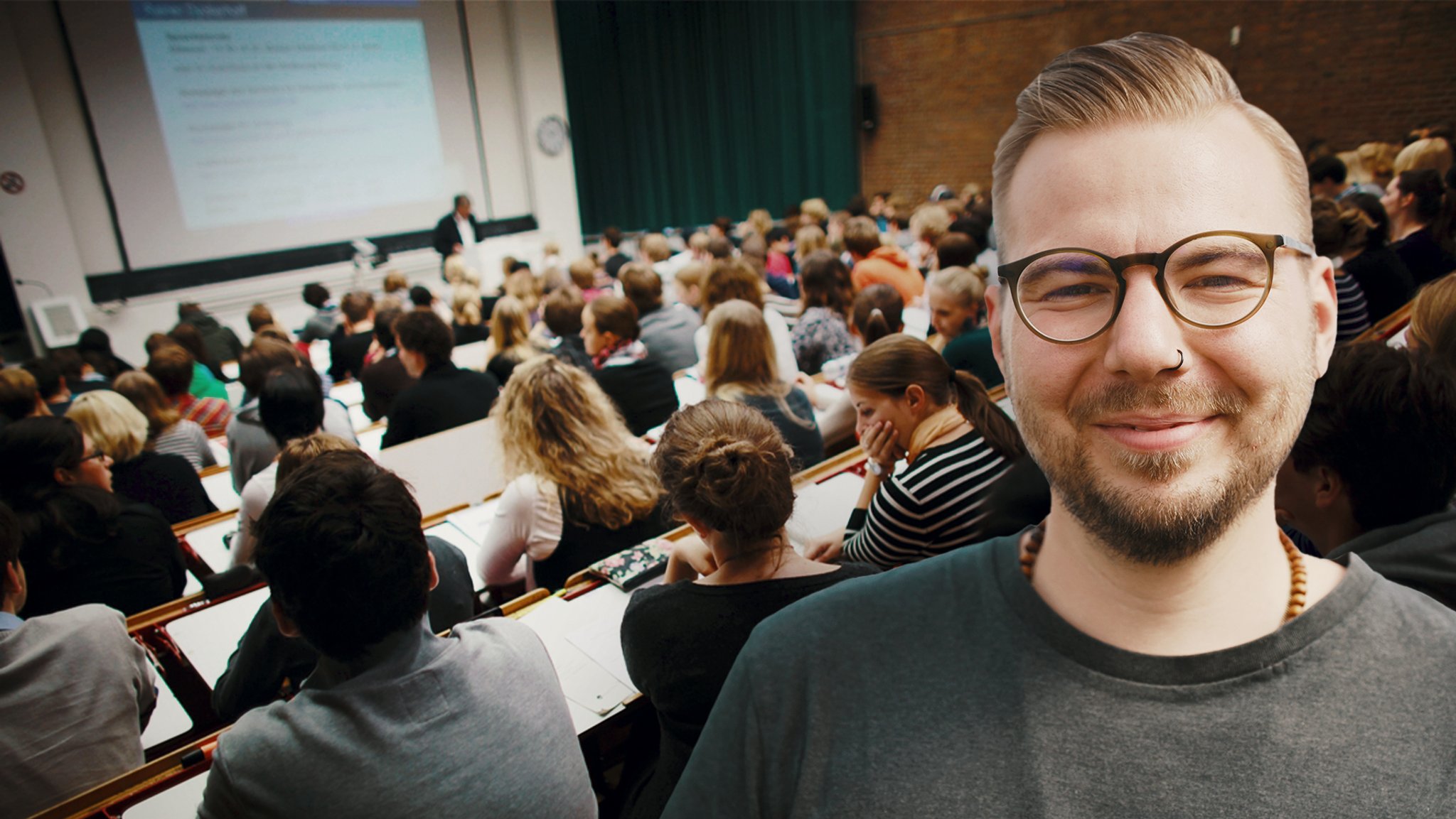 Ein Hörsaal voller Studierender, im Vordergrund ein junger Mann.