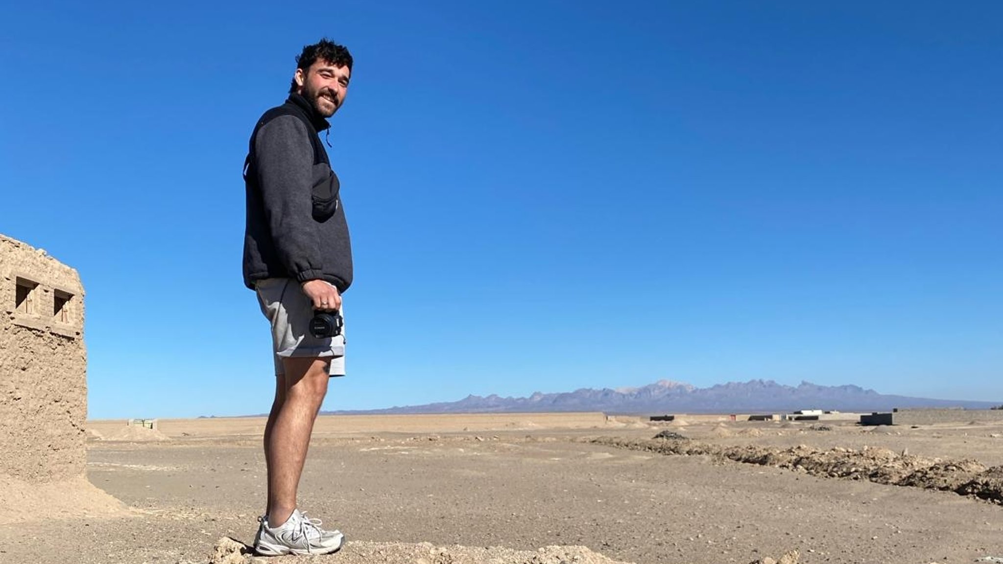 Valentin Oeckl steht mit einer Kamera in einer ländlichen Gegend von Pakistan.