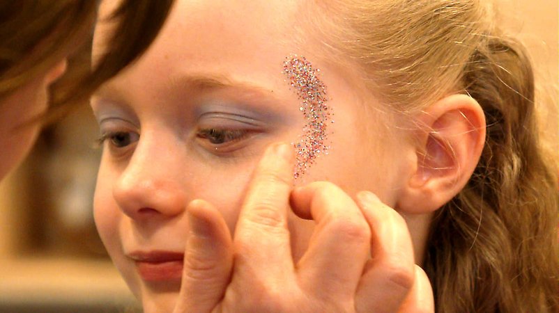 Ein Mädchen wird mit Glitter geschminkt. | Bild: BR Ein Mädchen wird mit Glitter geschminkt.