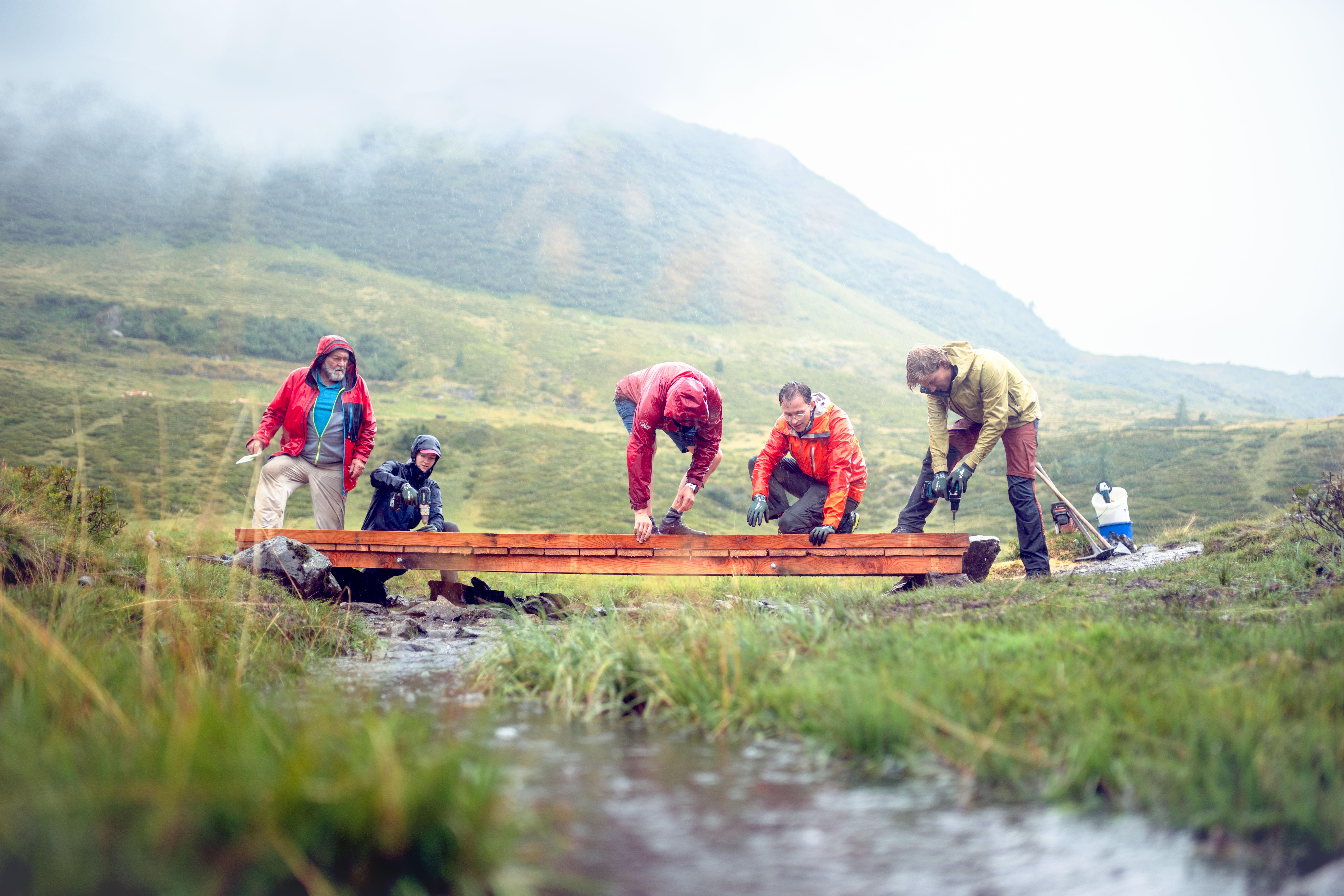 Fünf Freiwillige befestigen eine Metallbrücke in der Nähe der Zollnersee-Hütte in Kärnten.