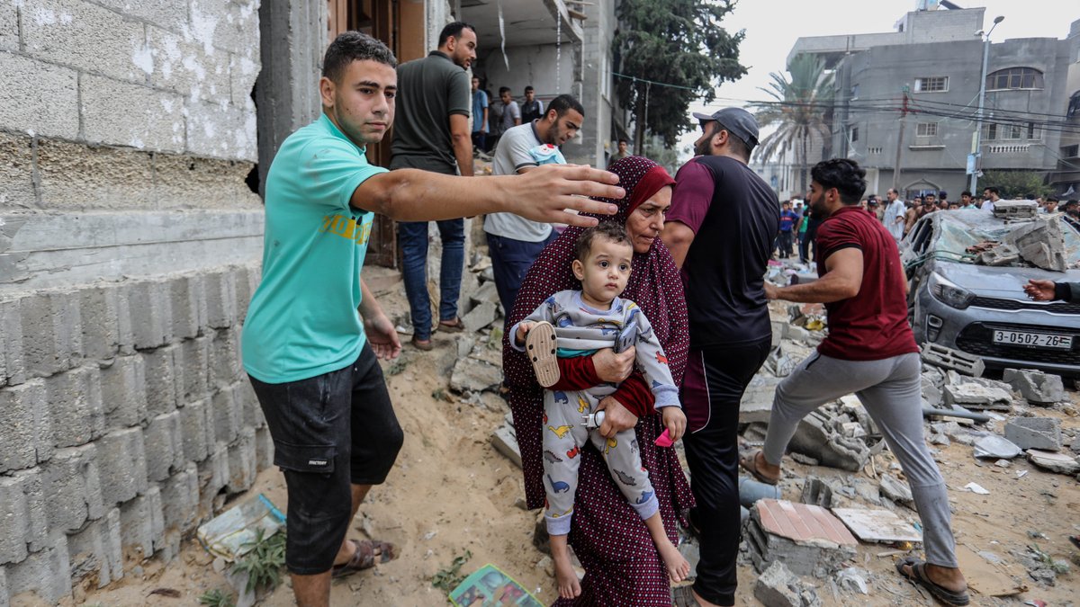 Palästinenser vor zerstörtem Haus im Gazastreifen