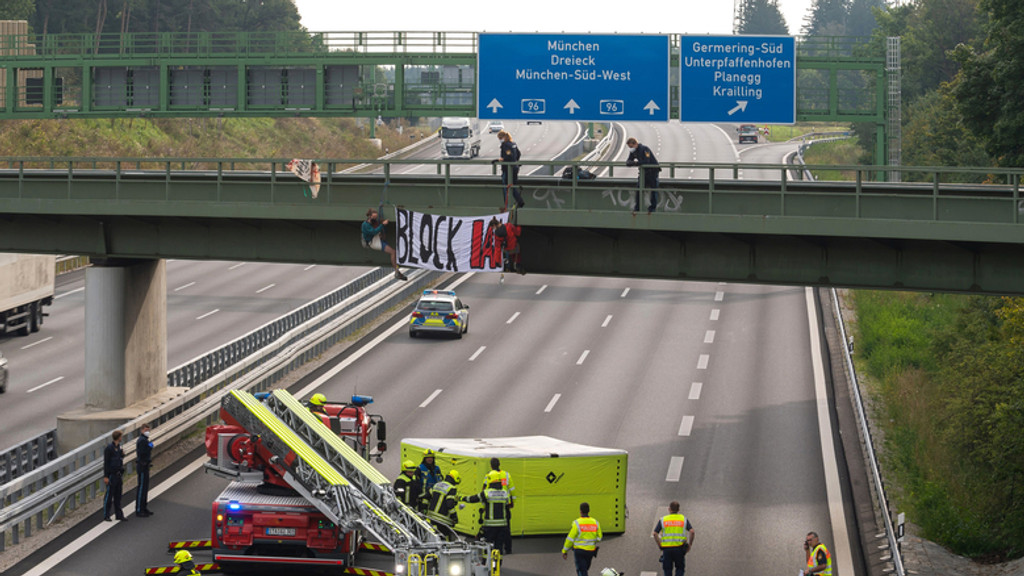 Aktivisten hängen ein Banner von einer Brücke über die Autobahn A96 bei Germering. Auf dem Banner steht "Block IAA". 
