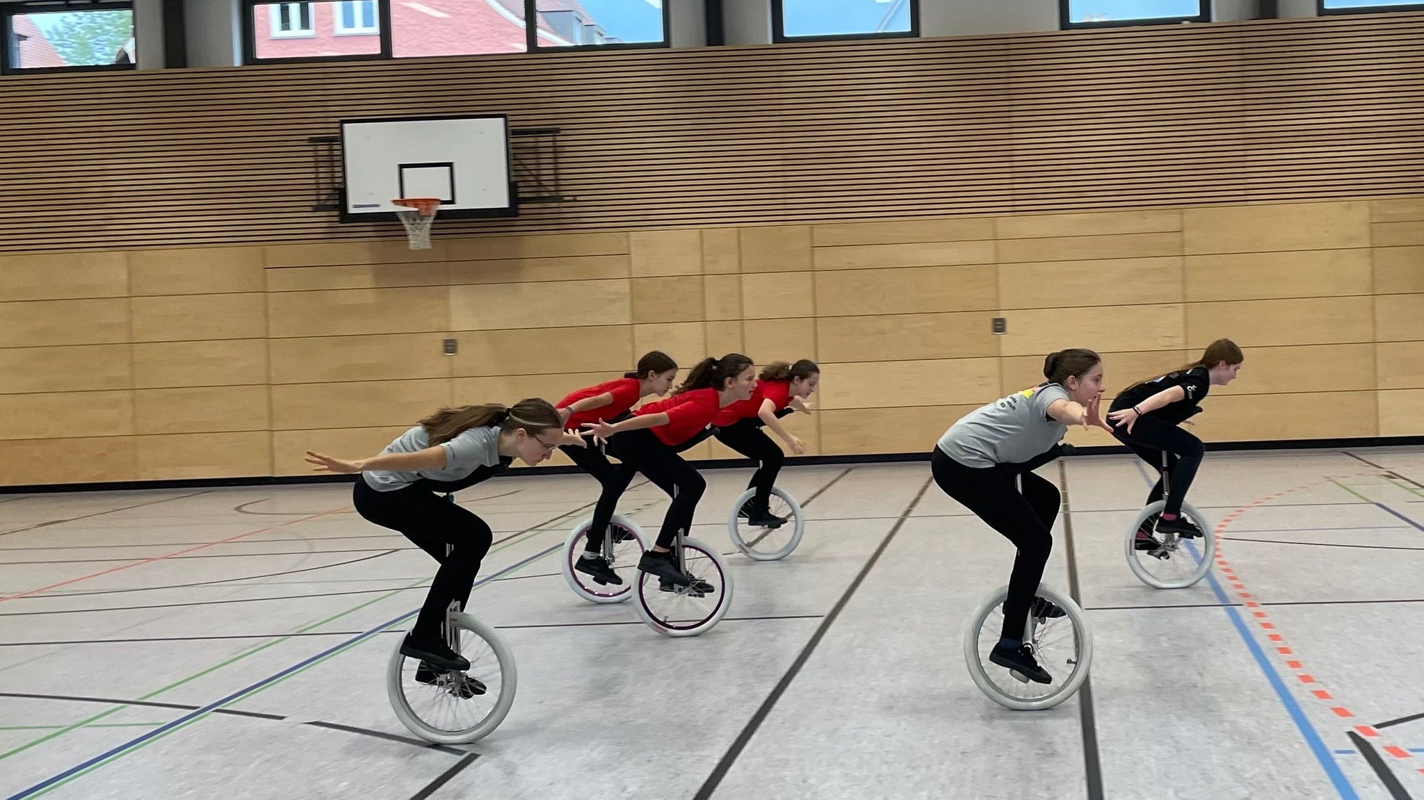 Einradfahrerinnen in einer Turnhalle.