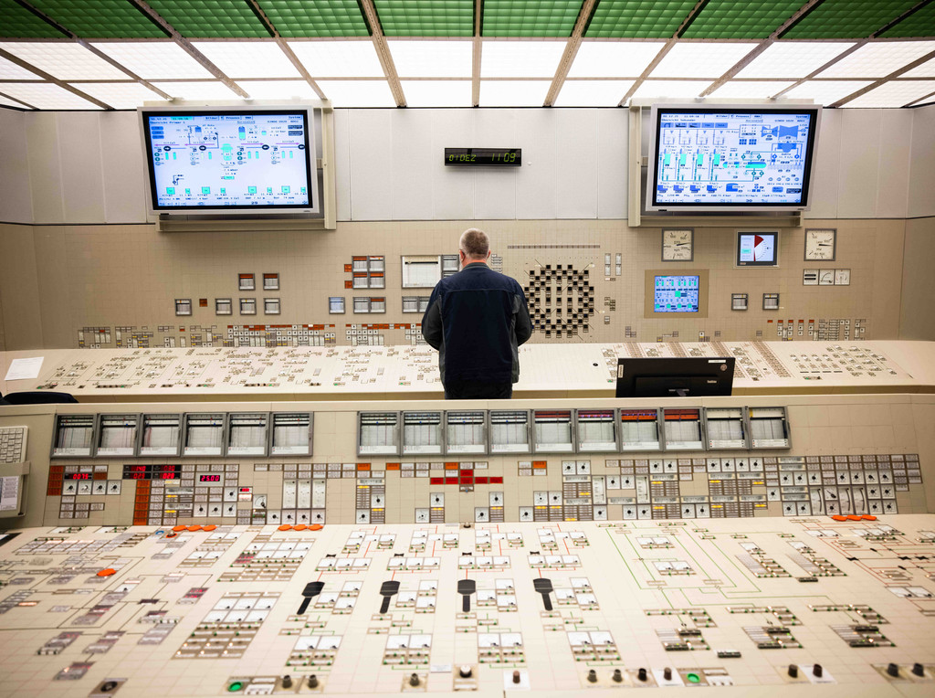 Ein Mitarbeiter steht an einem Kontroll- und Steuerungspult im Leitstand des Kernkraftwerks. 
