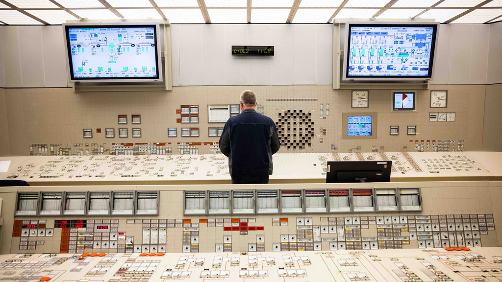 Ein Mitarbeiter steht an einem Kontroll- und Steuerungspult im Leitstand des Kernkraftwerks. 