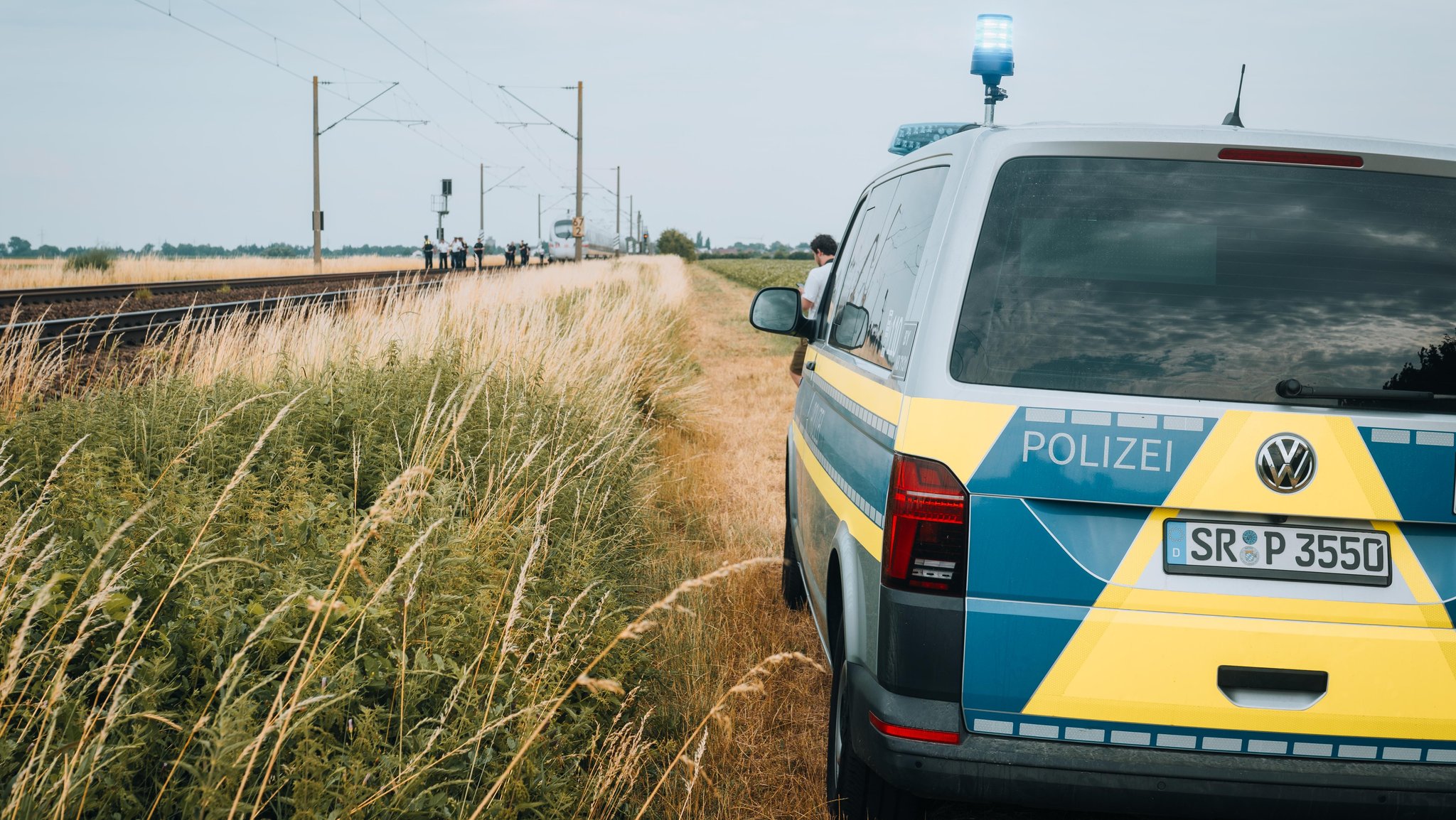 Ein Polizeibus neben der Zugstrecke, auf der ein ICE wegen eines Angriffs eine Notbremsung bei Straßkirchen einlegen musste.