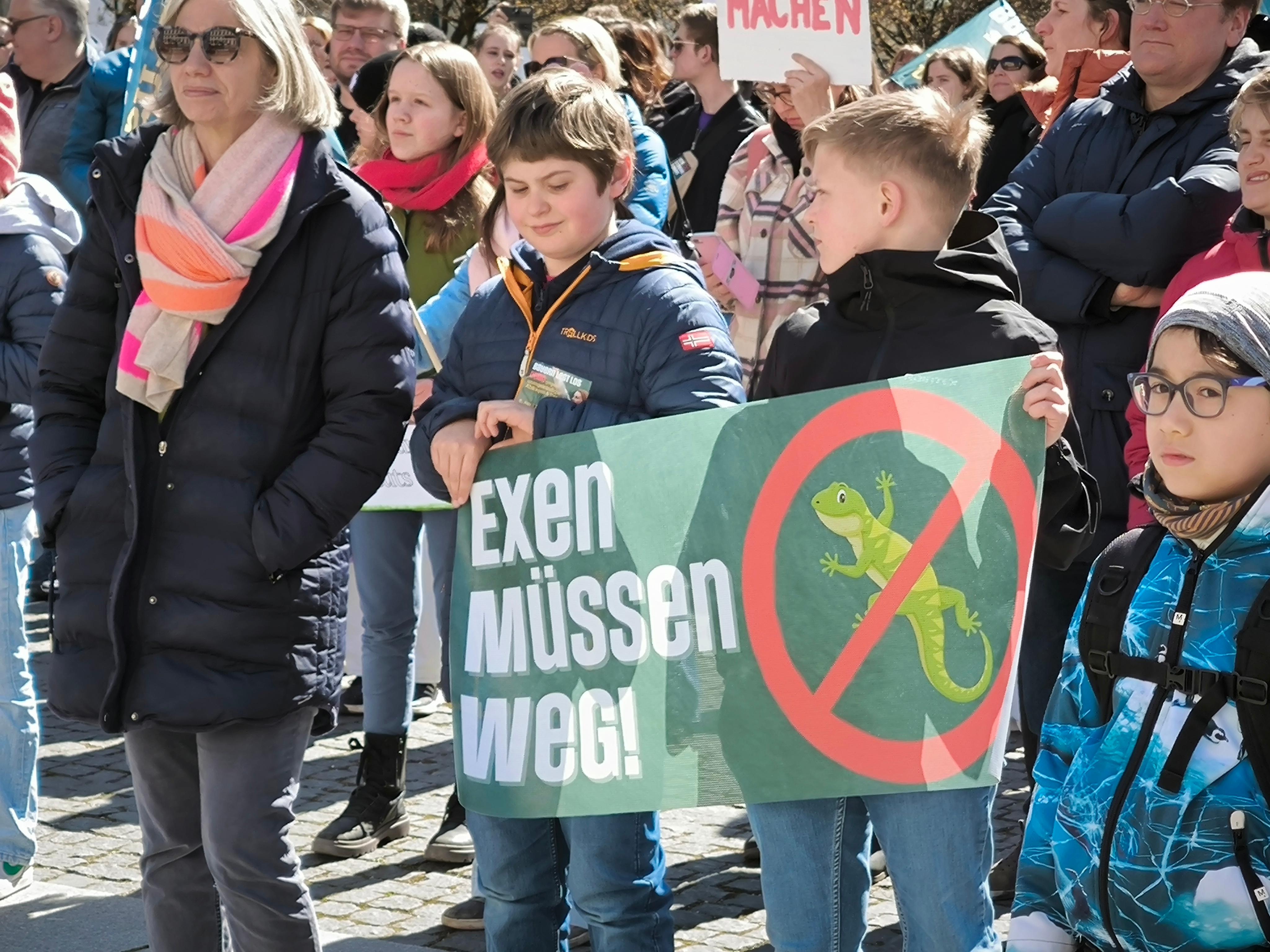 Zwei Kinder mit einem Plakat "Exen müssen weg"