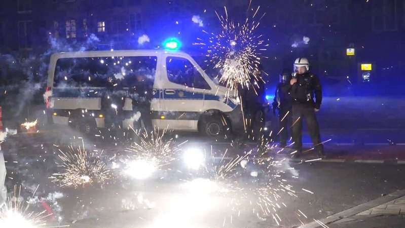 Berliner Polizeibeamte stehen in der Silvesternacht hinter explodierendem Feuerwerk.