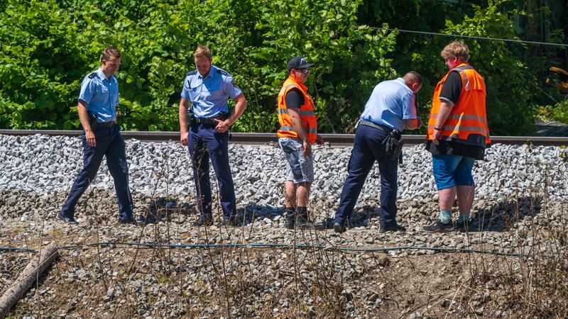 Polizisten und Bahn-Mitarbeiter betrachten am 14. Juni 2022 Schotterbett und Gleise an der Unfallstelle in Burgrain.