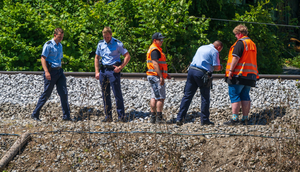 Polizisten und Bahn-Mitarbeiter betrachten am 14. Juni 2022 Schotterbett und Gleise an der Unfallstelle in Burgrain.