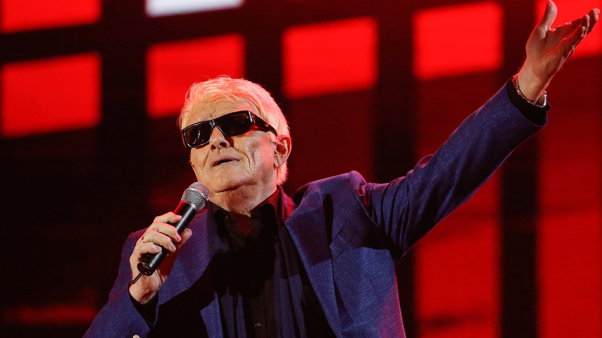 Der Sänger Heino auf der Bühne, in der einen Hand ein Mikrofon, die andere nach oben gestreckt