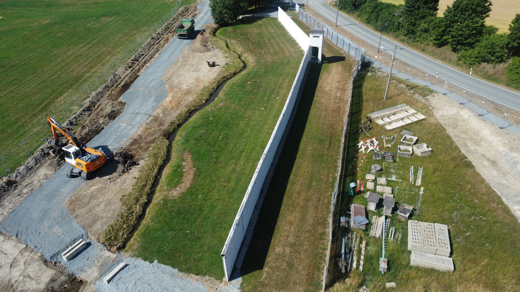 Ein Luftbild zeigt Bauarbeiten an einer Mauer.