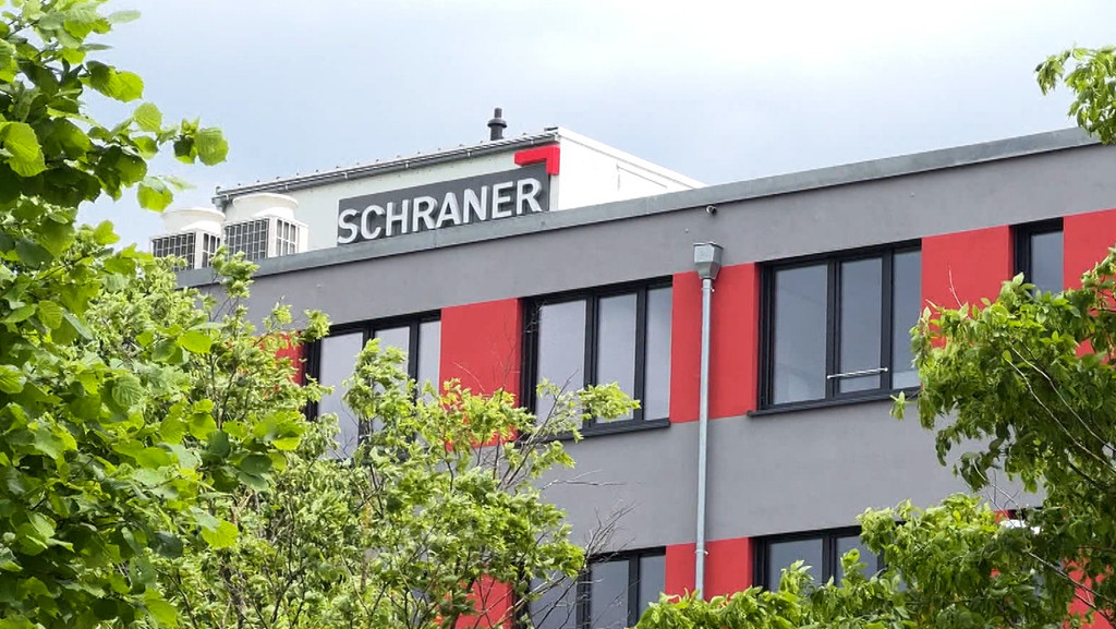 Ein Firmengebäude mit der Aufschrift "Schraner", davor Bäume.  