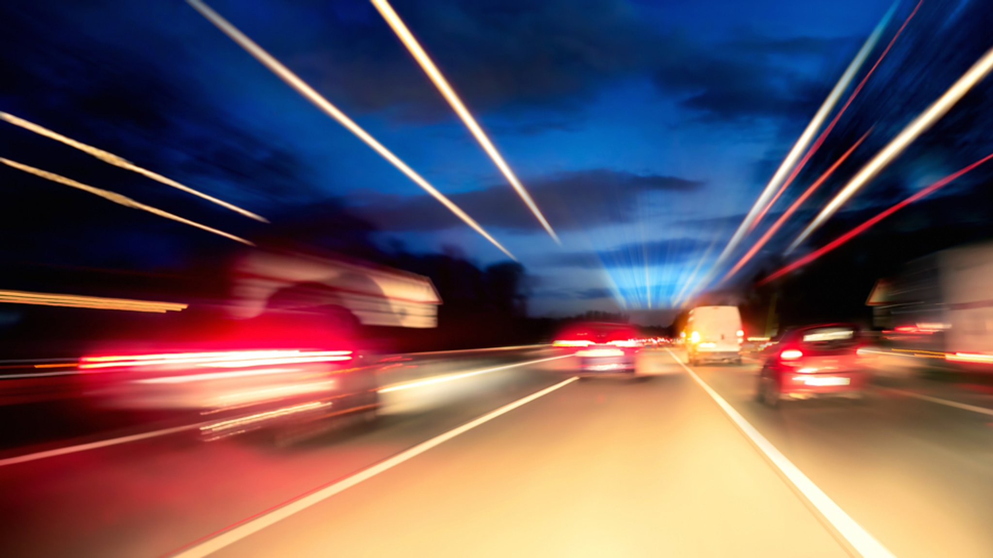 Autos auf der nächtlichen Autobahn mit Lichtspuren.