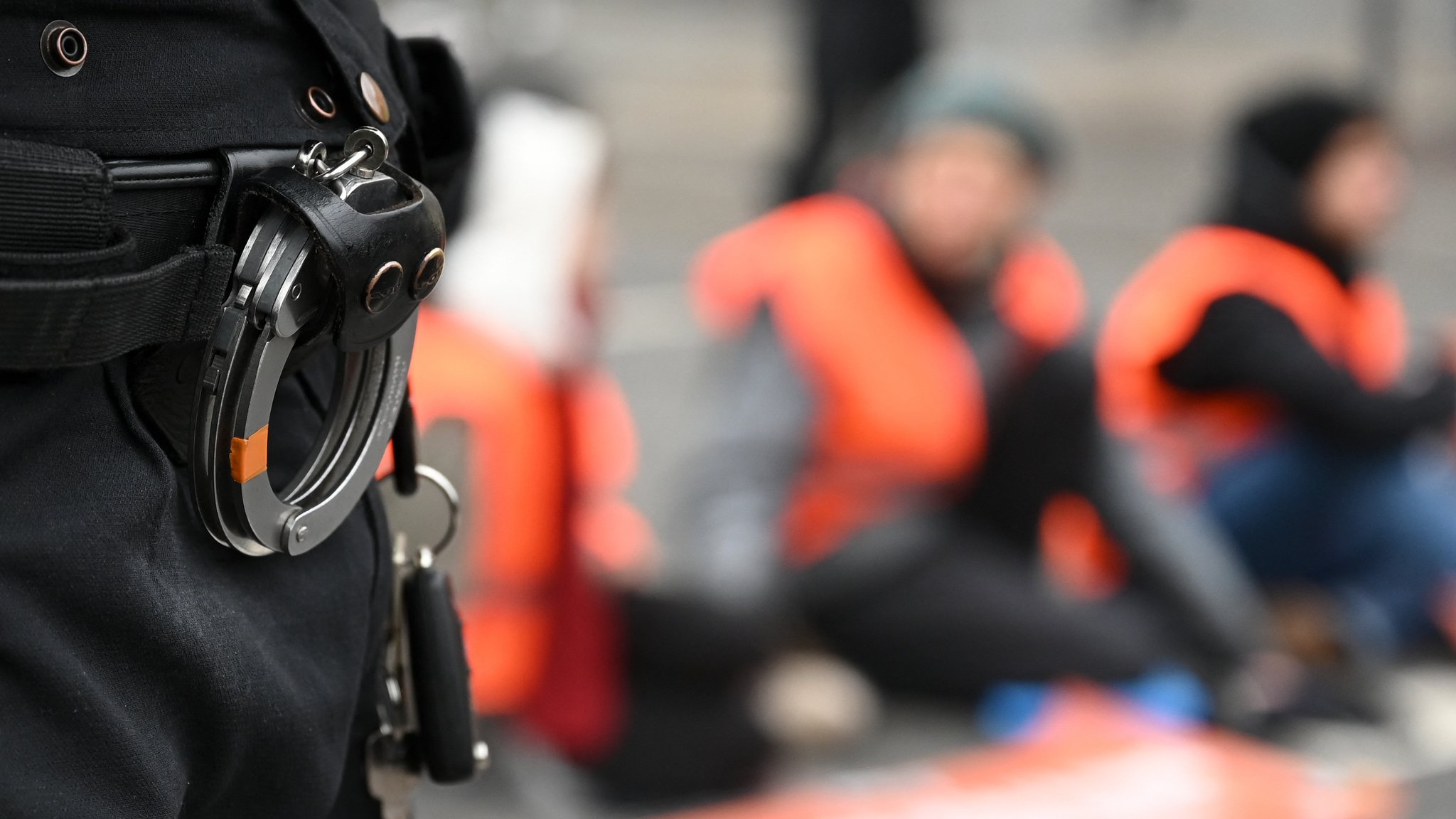 Ein Polizist steht bei Klima-Aktivisten, die sich in München auf die Straße geklebt haben