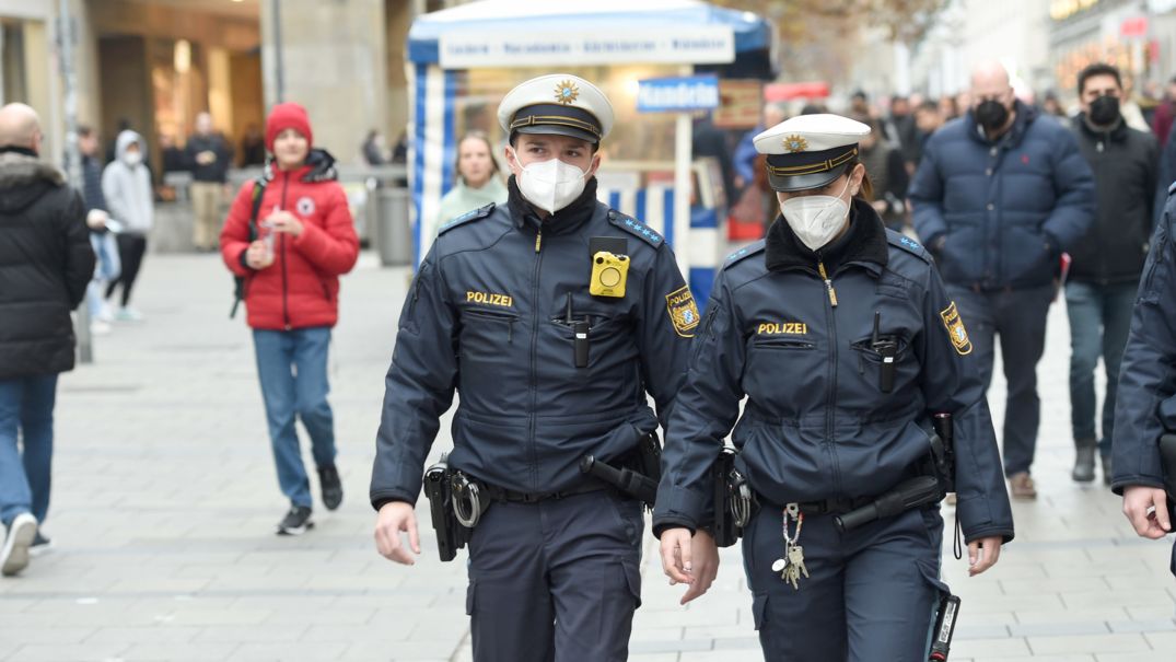 Polizeibeamte gehen bei einem Pressetermin zu Corona-Kontrollen in München durch die Fußgängerzone.