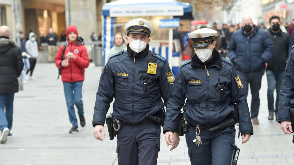 Polizeibeamte gehen bei einem Pressetermin zu Corona-Kontrollen in München durch die Fußgängerzone.
