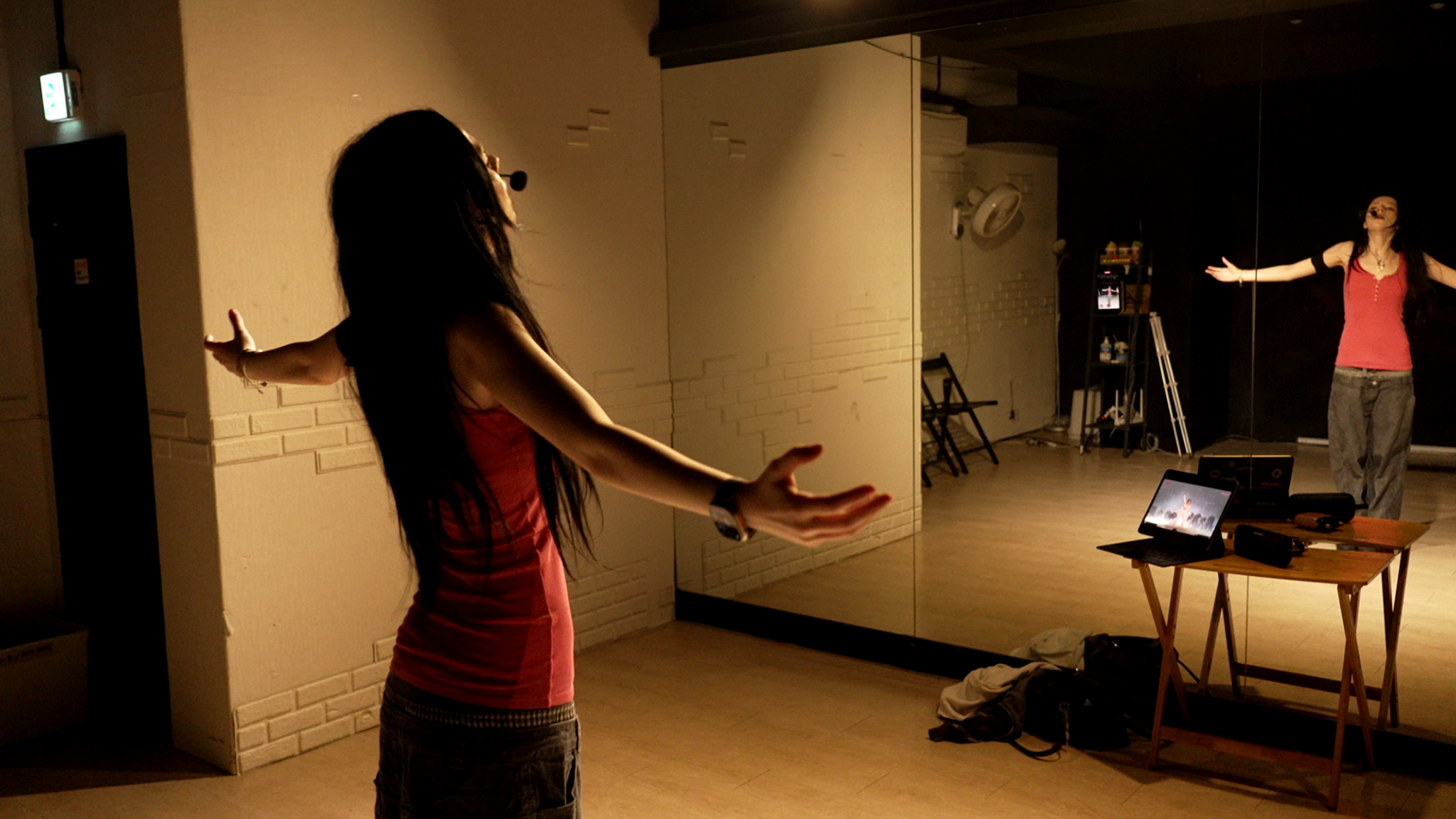 Eine junge Frau mit Headset steht in einem Tanzstudio vor dem Spiegel und macht eine Performance. | Bild: BR/Justus Flöter Eine junge Frau mit Headset steht in einem Tanzstudio vor dem Spiegel und macht eine Performance.