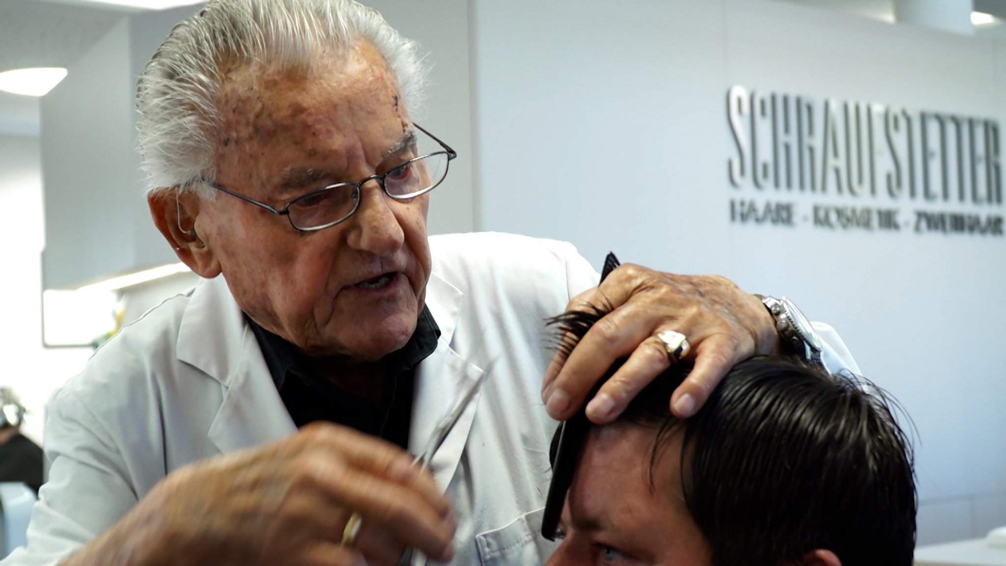 Der 93-jährige Friseur schneidet einem Kunden die Haare.